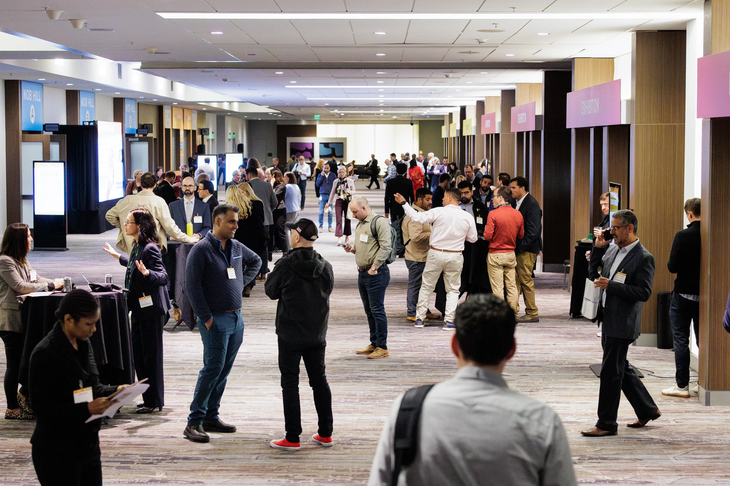 Large group of badged attendees networking in wide conference hallway during Orlando corporate event