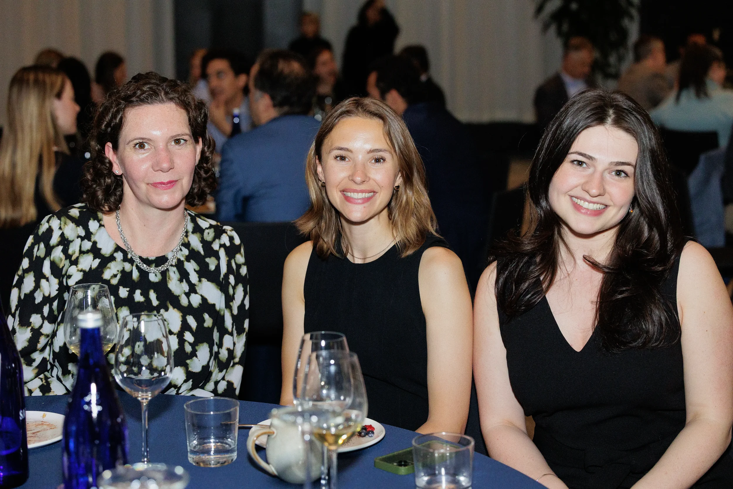 Three attendees smile together at dinner table during Chicago corporate awards event