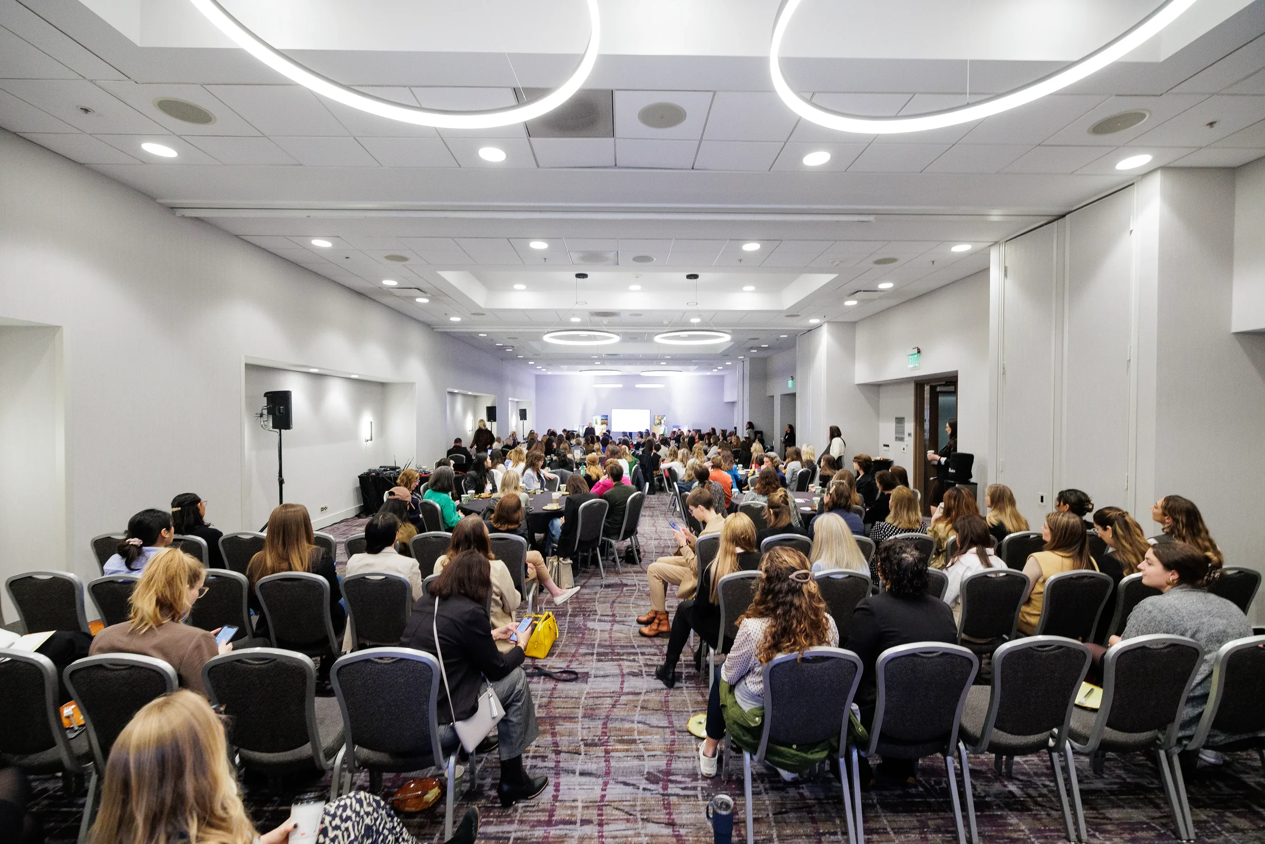 Wide shot of full room of female attendees seated at tables during Chicago corporate conference breakfast session