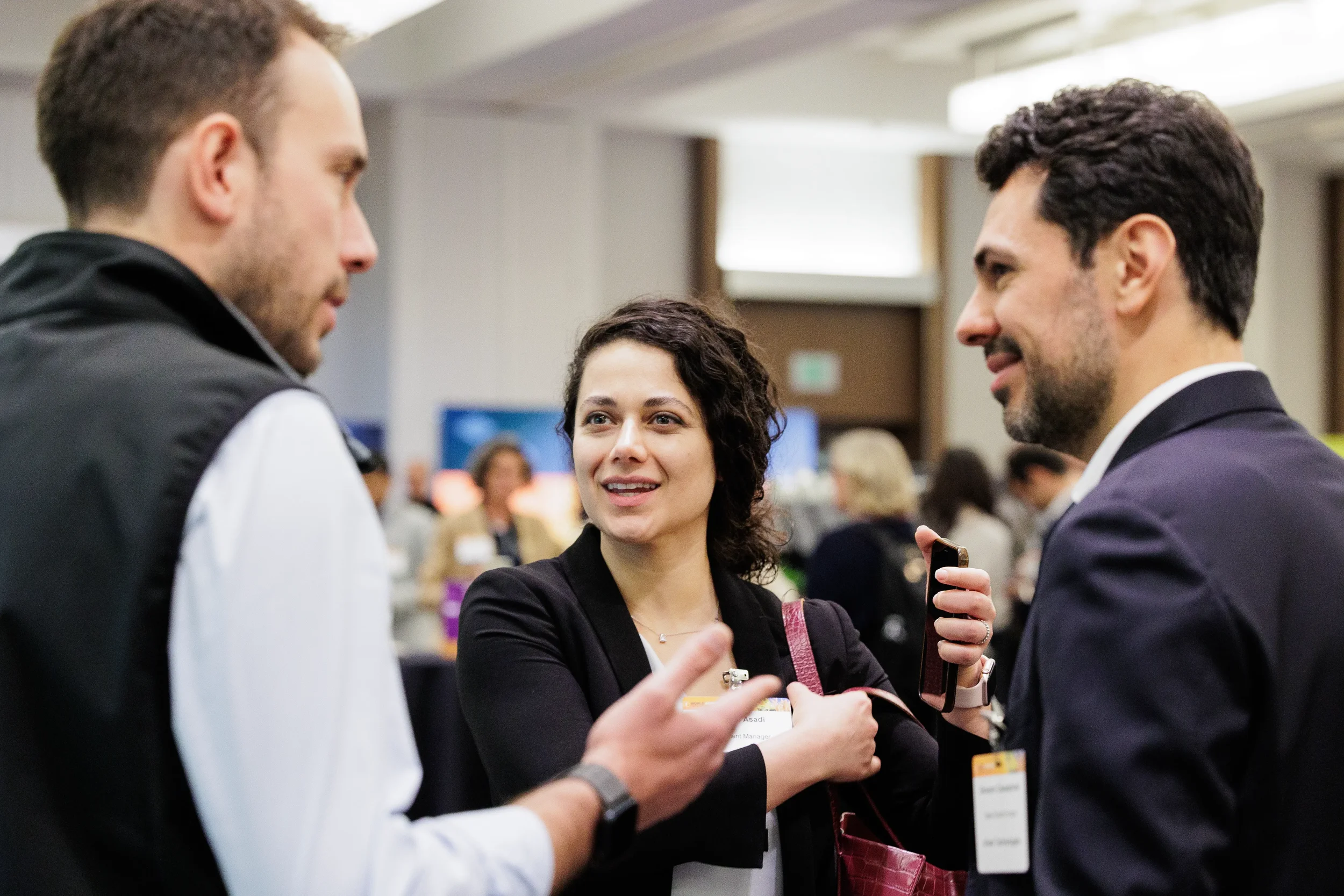 Three badged attendees engaged in lively conversation during networking break at Chicago corporate conference