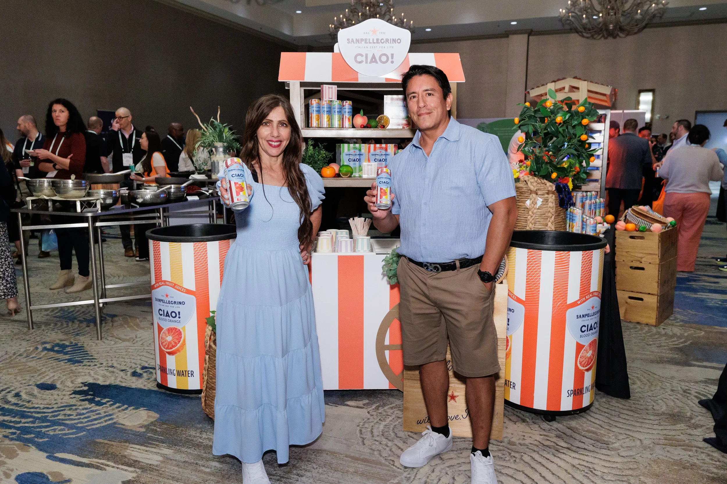 Two attendees hold up branded cans in front of themed exhibitor booth at Chicago corporate conference expo