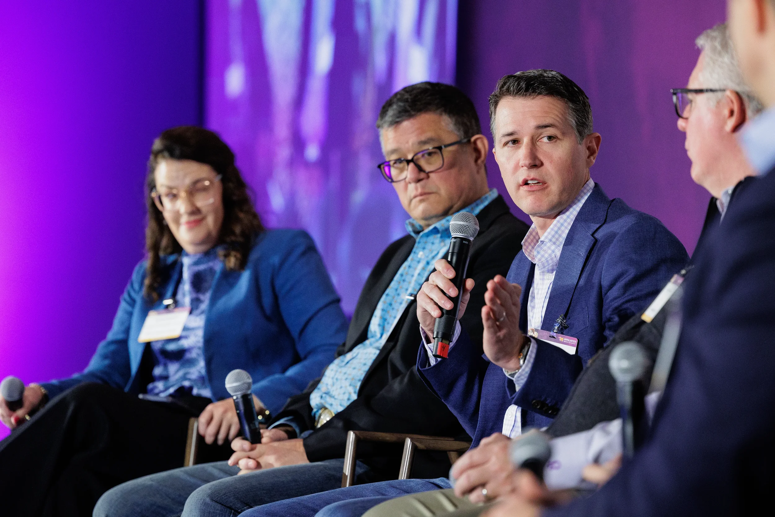 Panelist gestures while speaking into microphone during seated discussion at Chicago summit