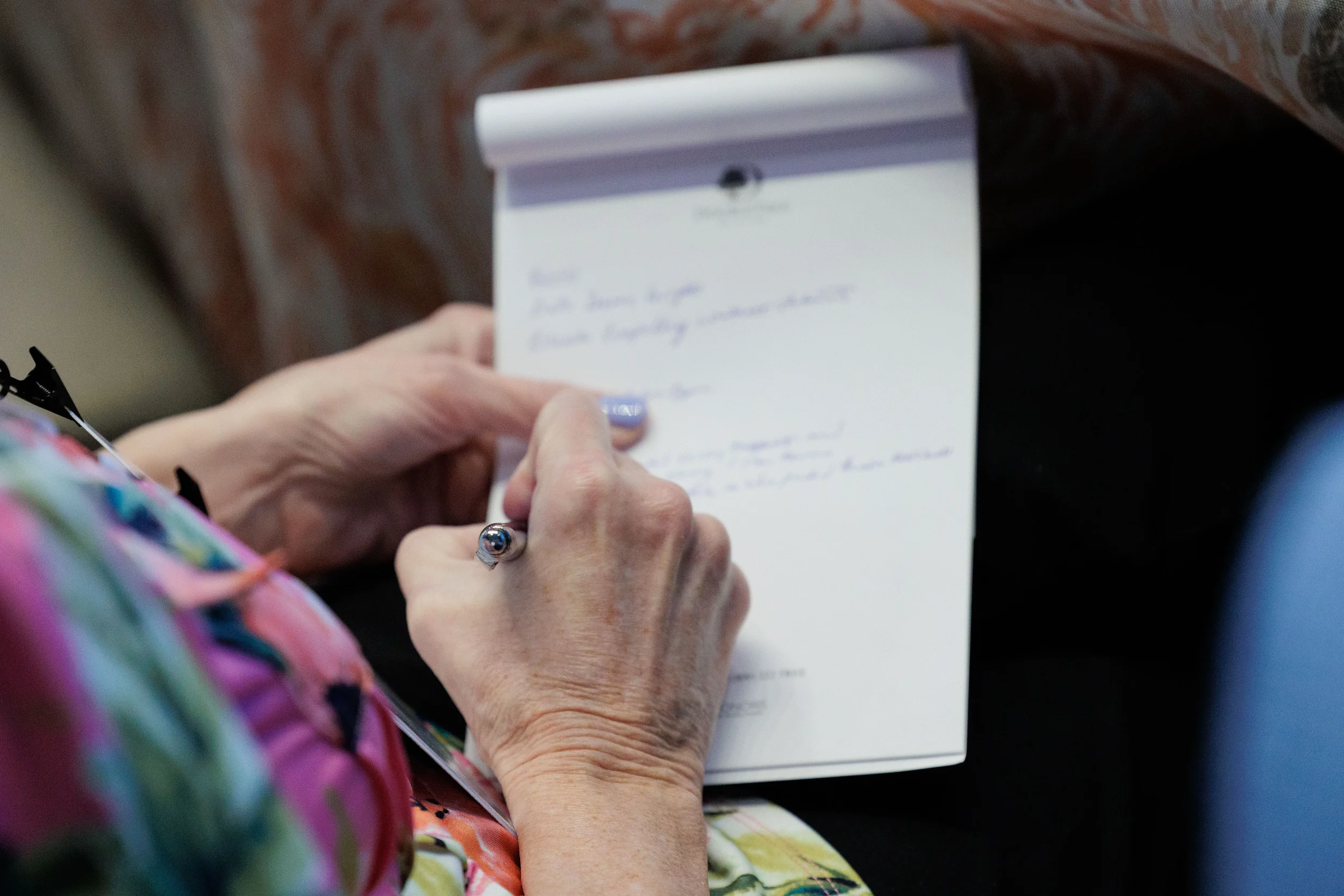 Close-up of attendee hand taking notes on branded notepad during Chicago industry conference session