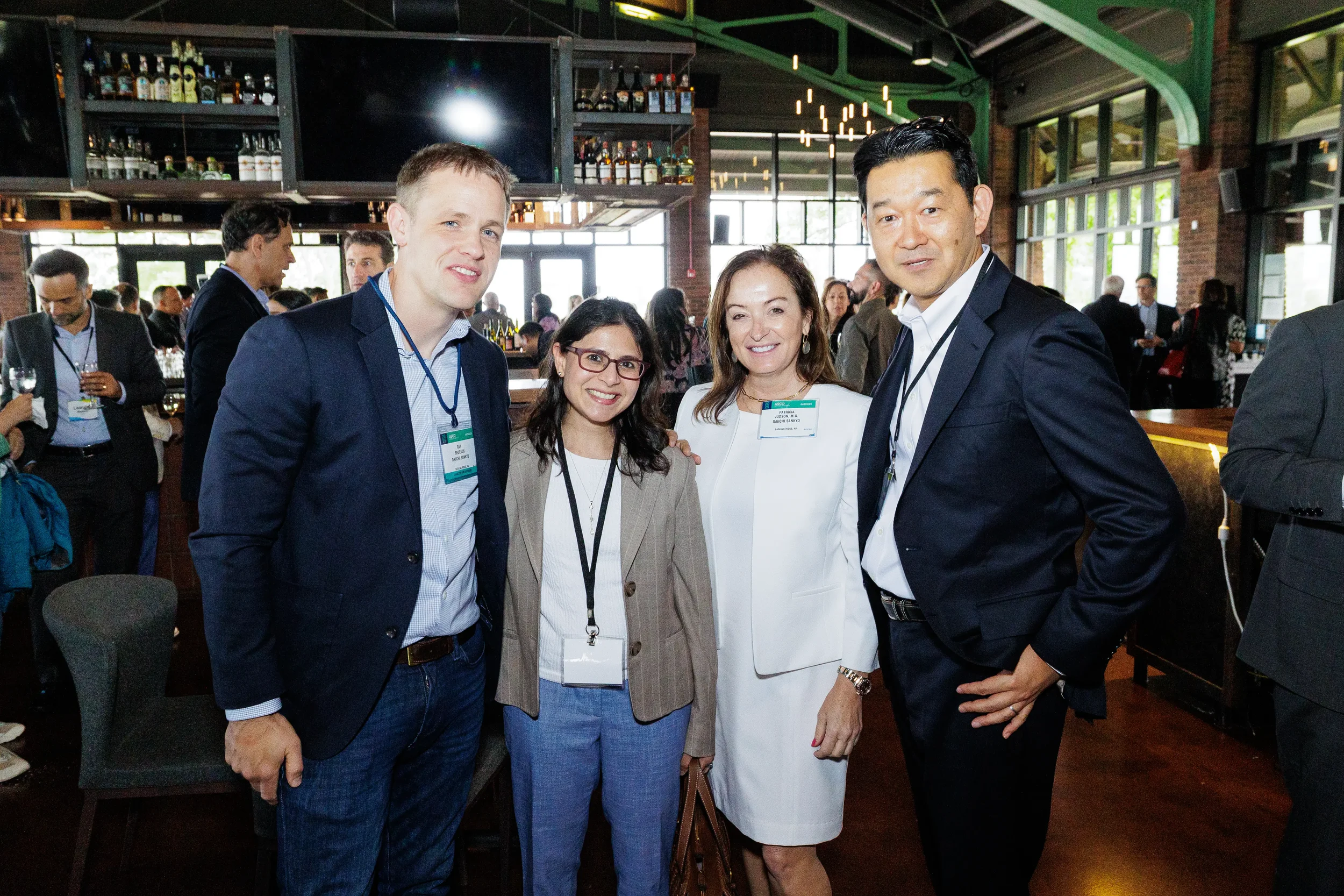 Four attendees with lanyards pose together during networking reception at Chicago industry event