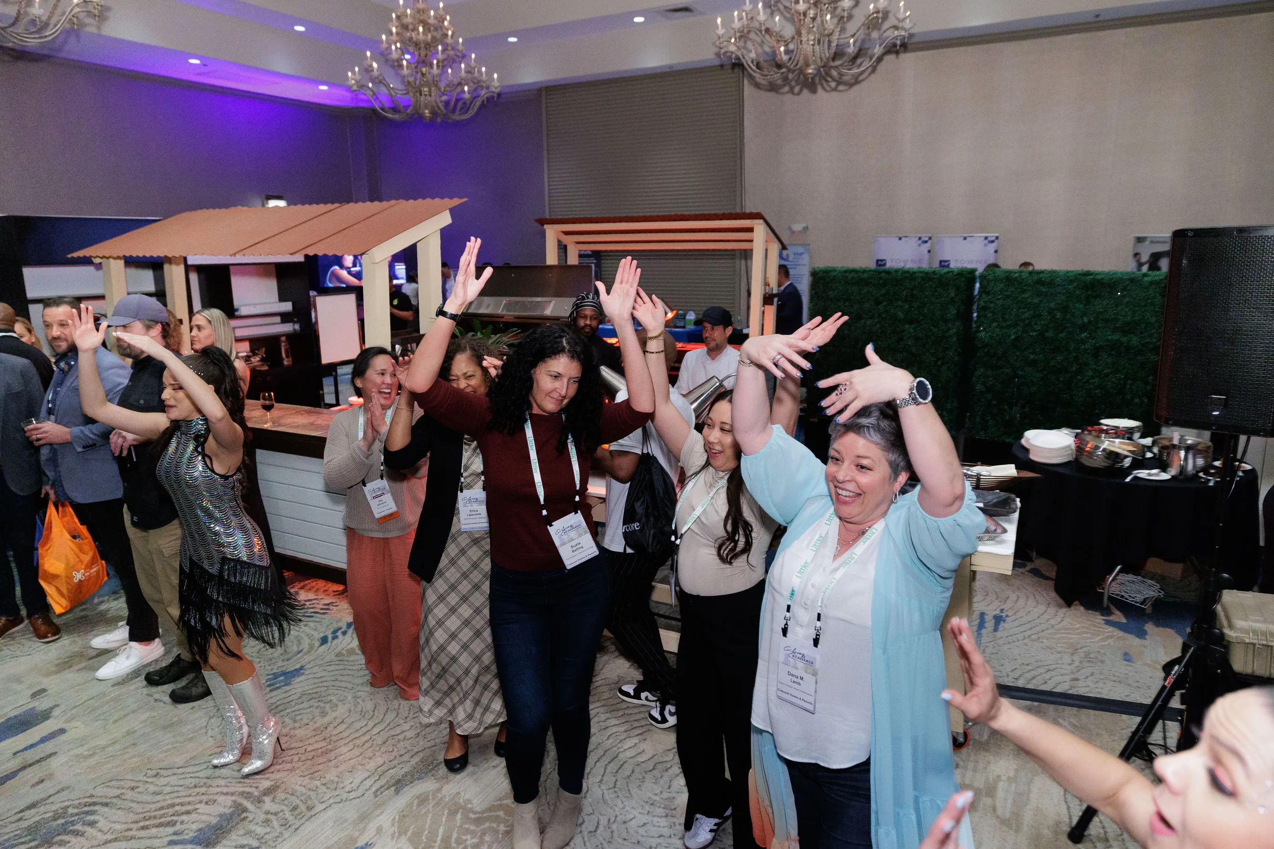 Group of attendees with lanyards dance with hands raised at Chicago corporate conference evening reception