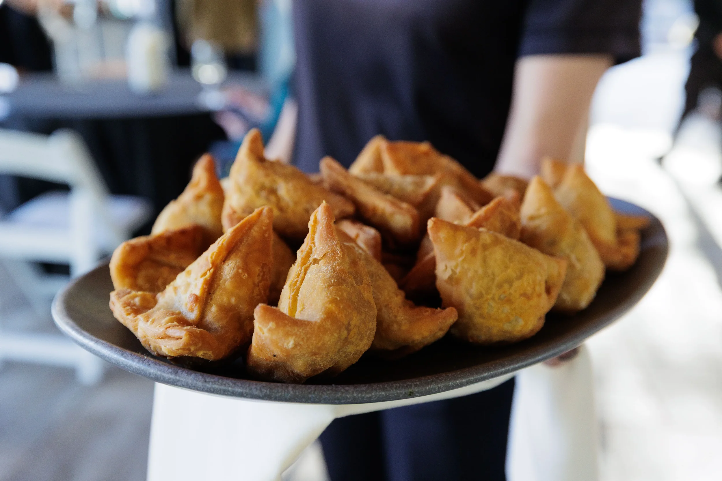 Server holds tray of golden fried pastry appetizers at Orlando corporate event reception