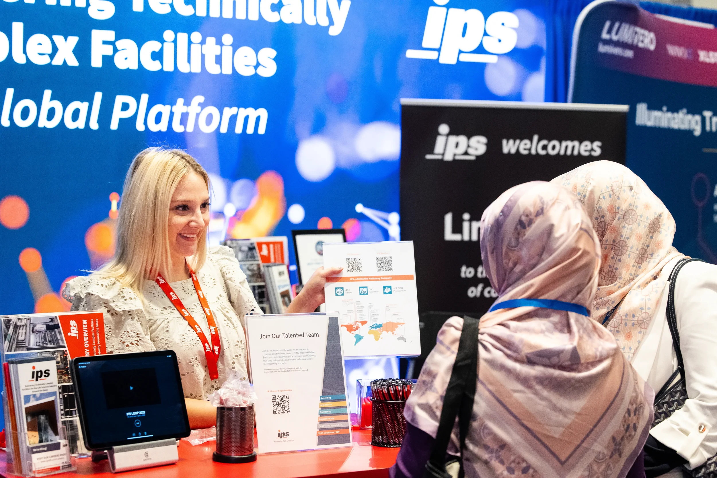 Exhibitor shares recruitment materials with attendee at trade show booth during AACE Orlando event