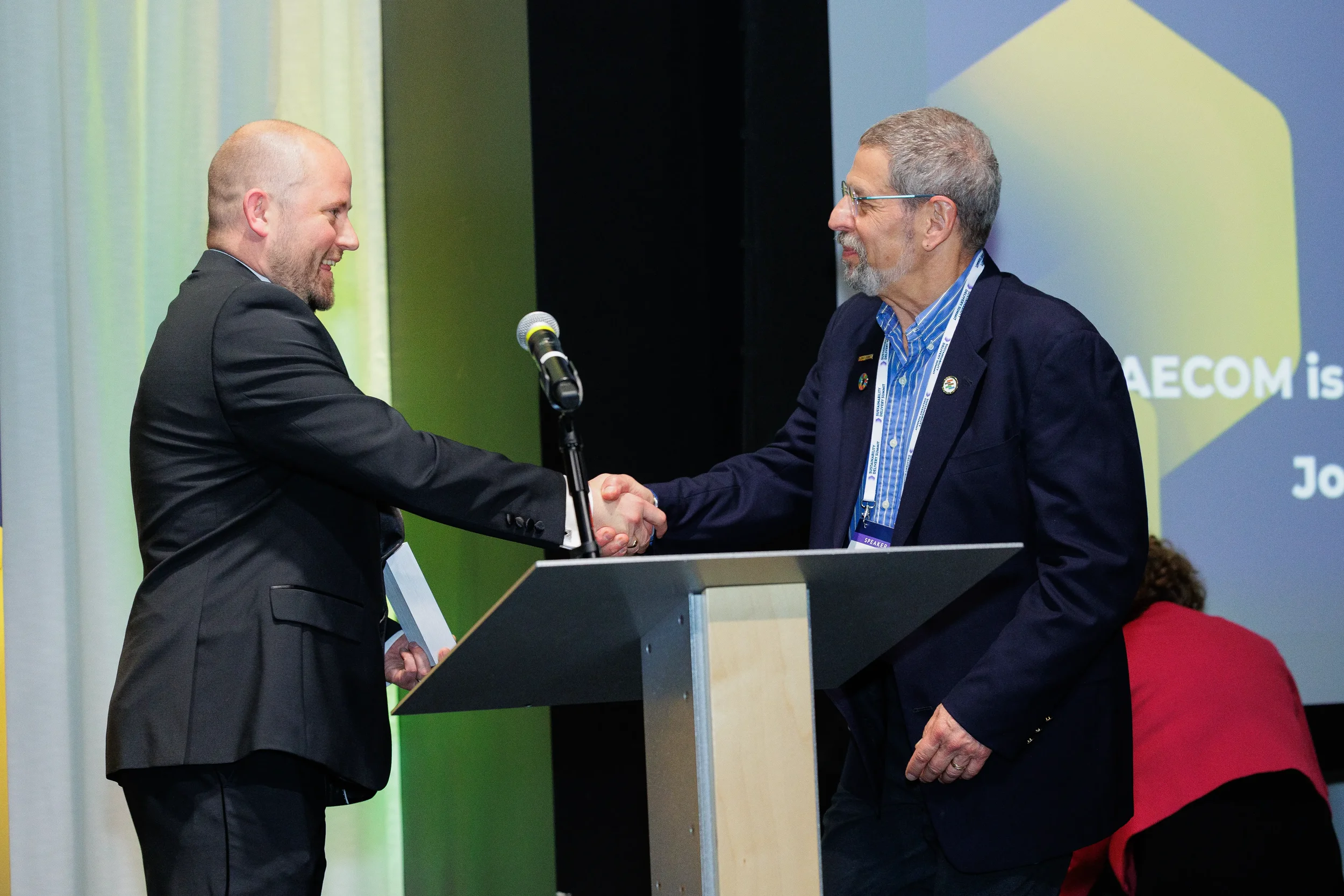 Two speakers shake hands at podium on stage during Chicago corporate awards ceremony