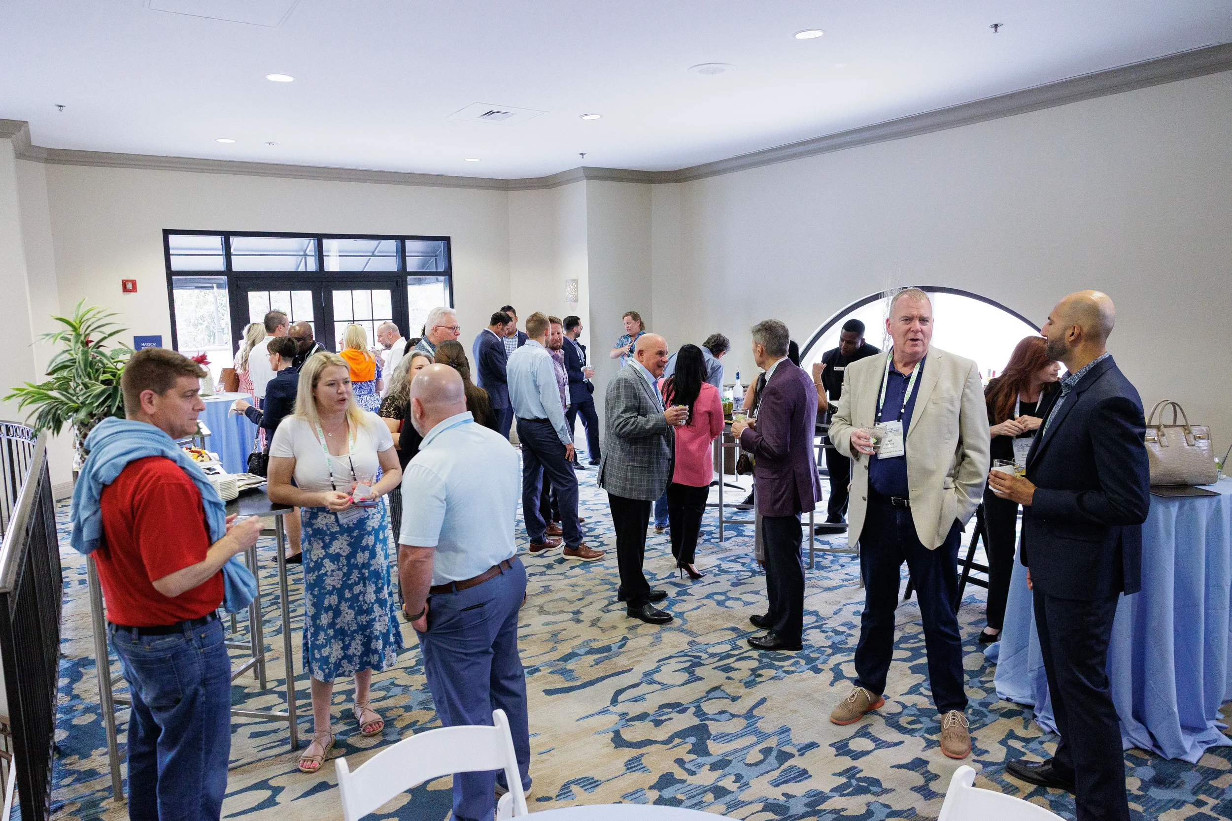 Large group of attendees mingle during networking reception in ballroom with arched doorway at Chicago conference