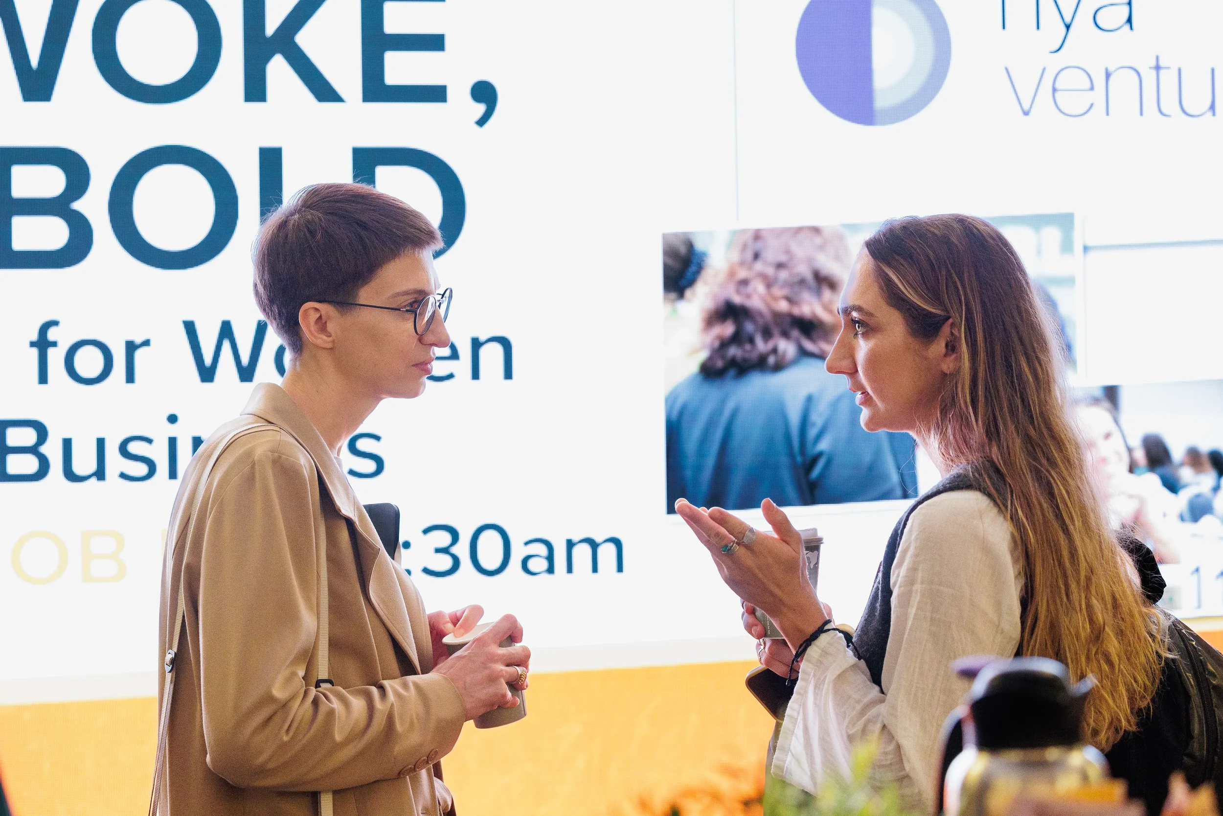 Two attendees with name badges engage in conversation in front of exhibitor booths at Chicago trade show