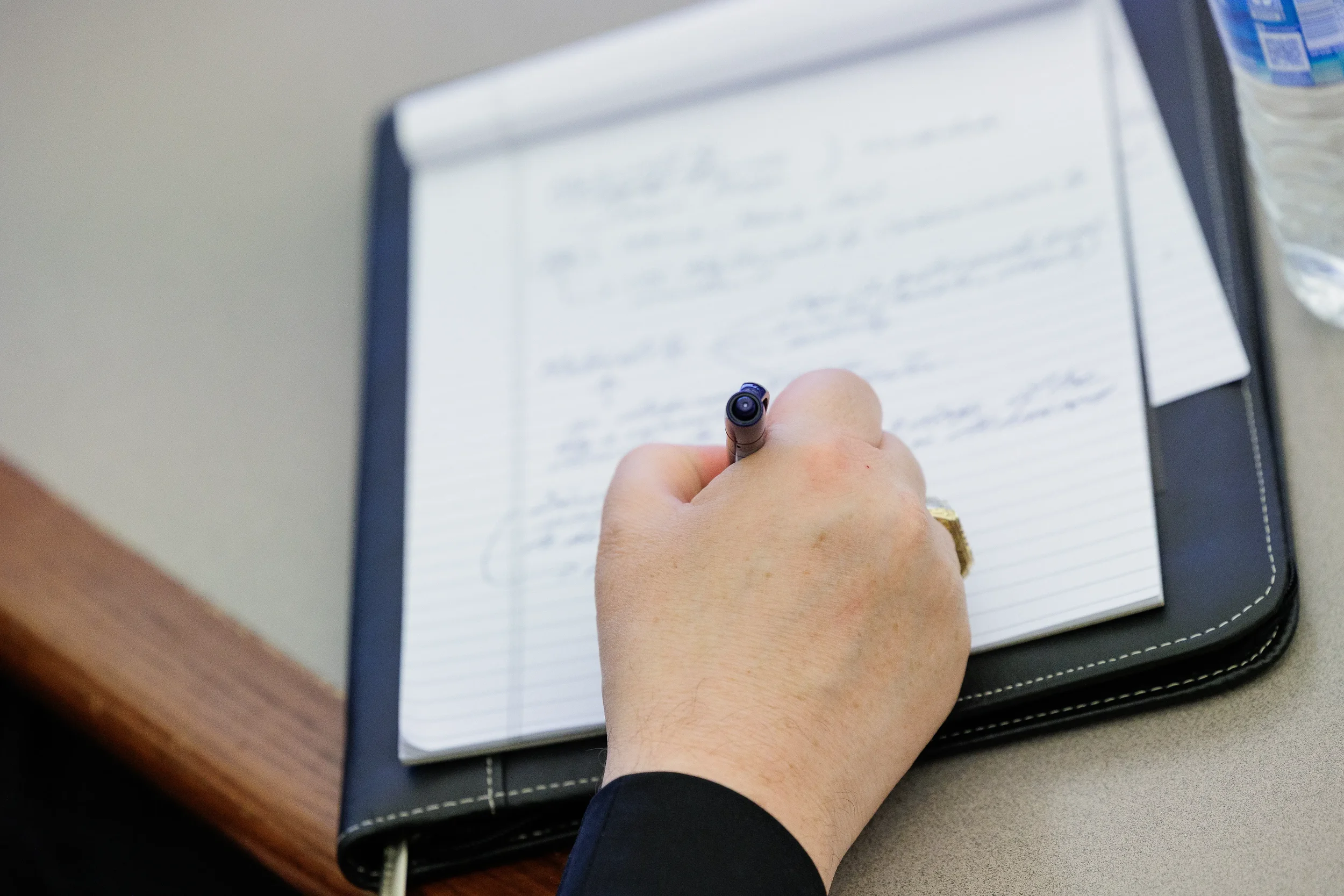 Attendee takes handwritten notes in leather portfolio during Orlando industry conference session