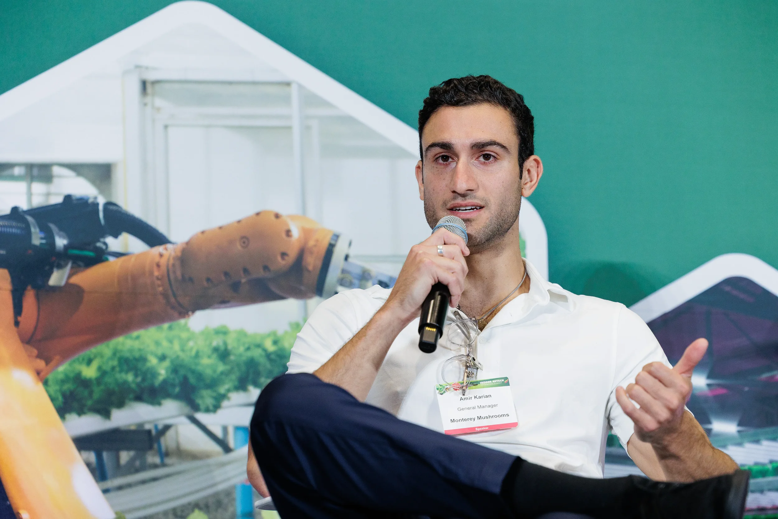 Speaker gestures while sharing insights into microphone during panel at Orlando industry event