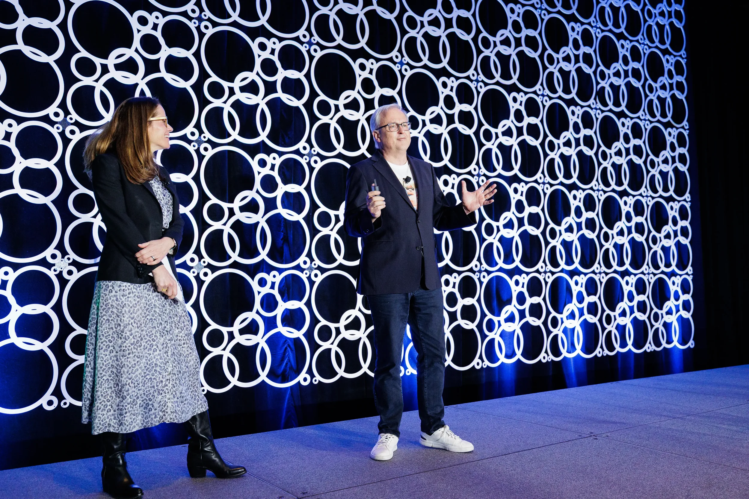 Two speakers converse on stage with illuminated circular backdrop at Orlando industry conference