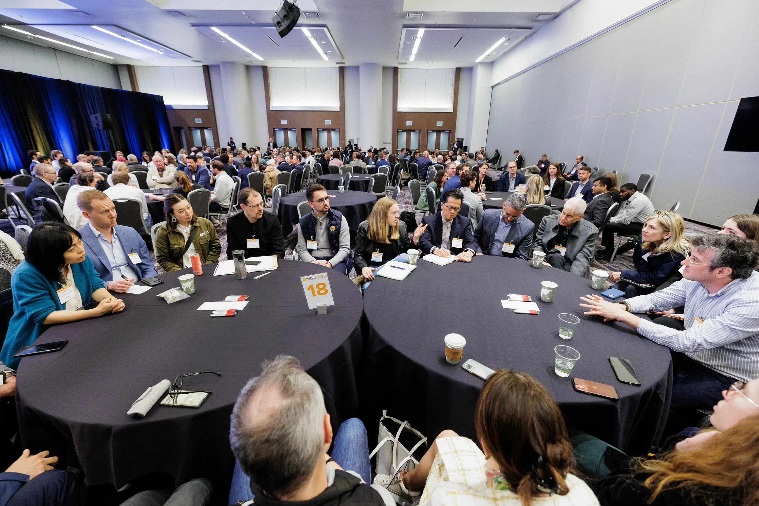 Wide shot of badged attendees seated at round tables during networking session at Chicago industry conference