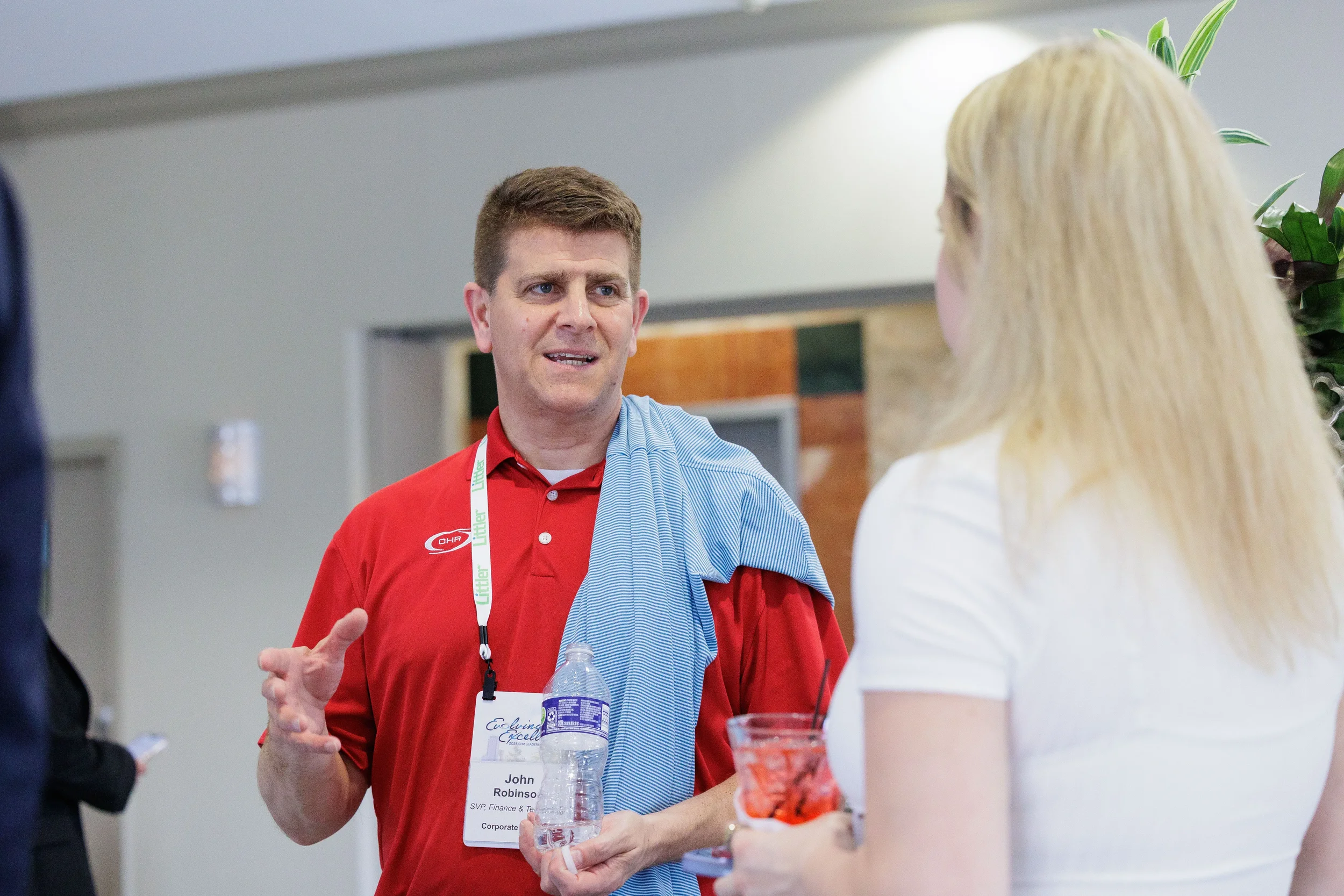 Male attendee with lanyard gestures expressively while networking at Orlando industry conference