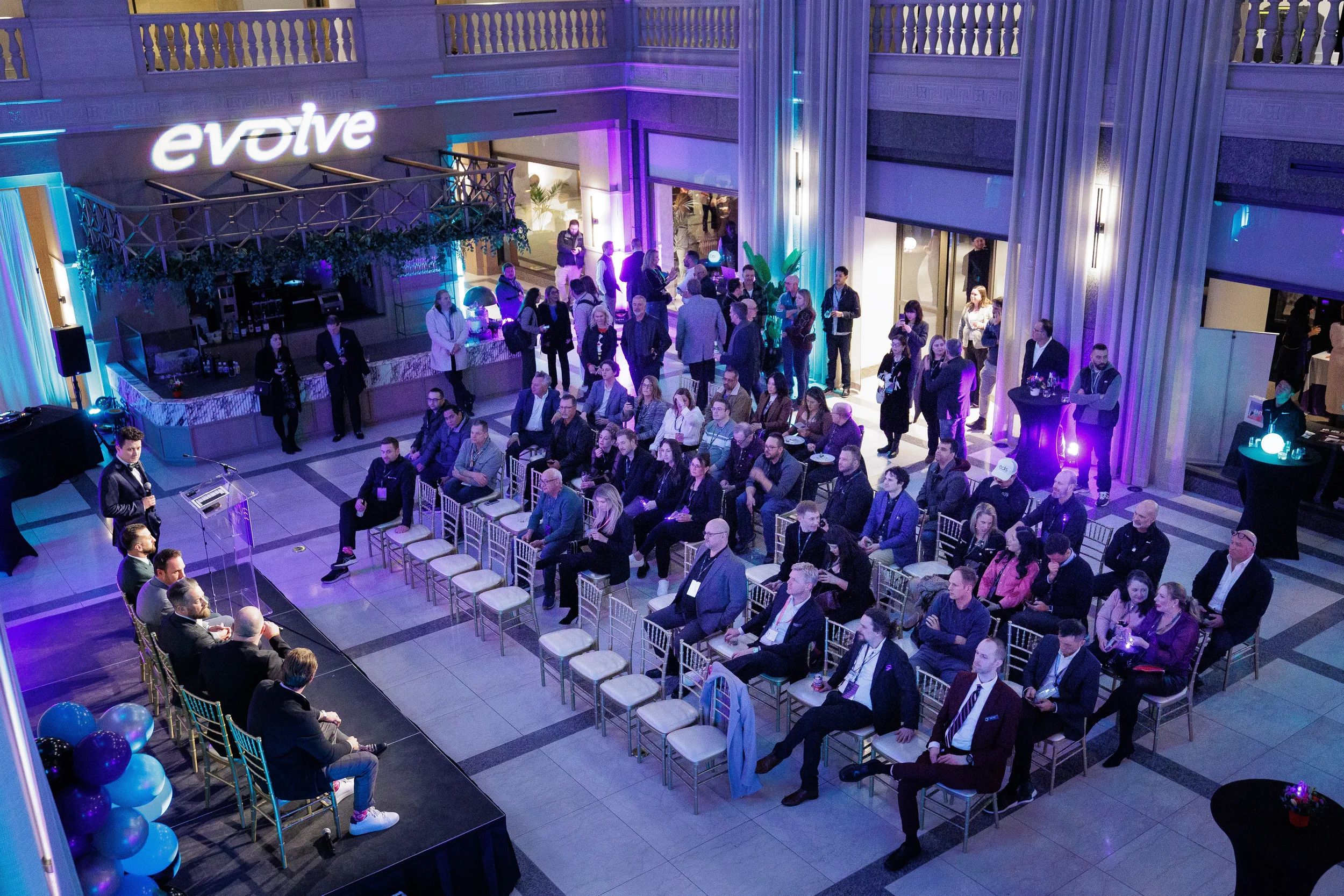 Aerial view of full audience seated in grand atrium with branded signage at Orlando corporate networking event