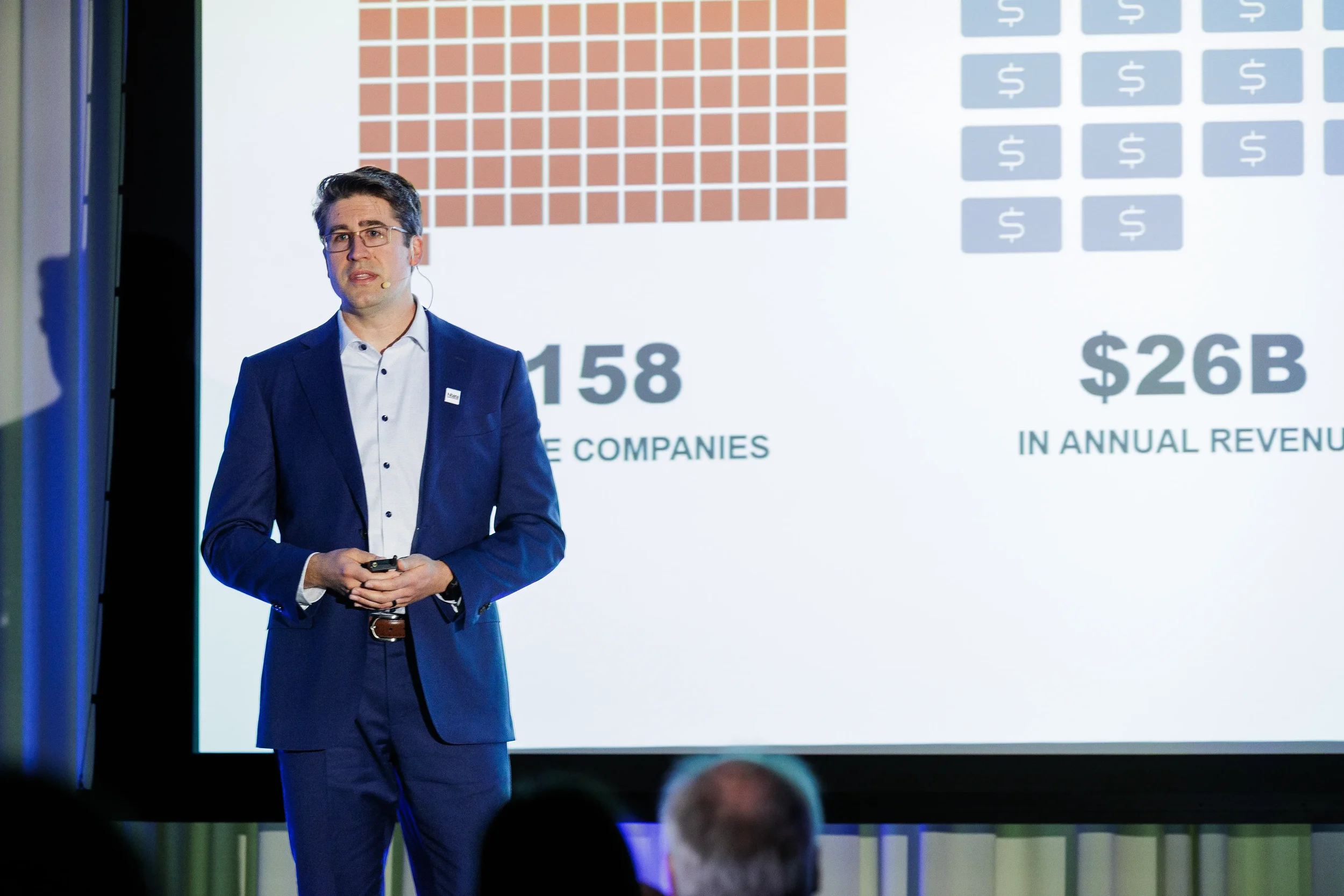Presenter in blue suit stands before data slide during session at Orlando industry conference