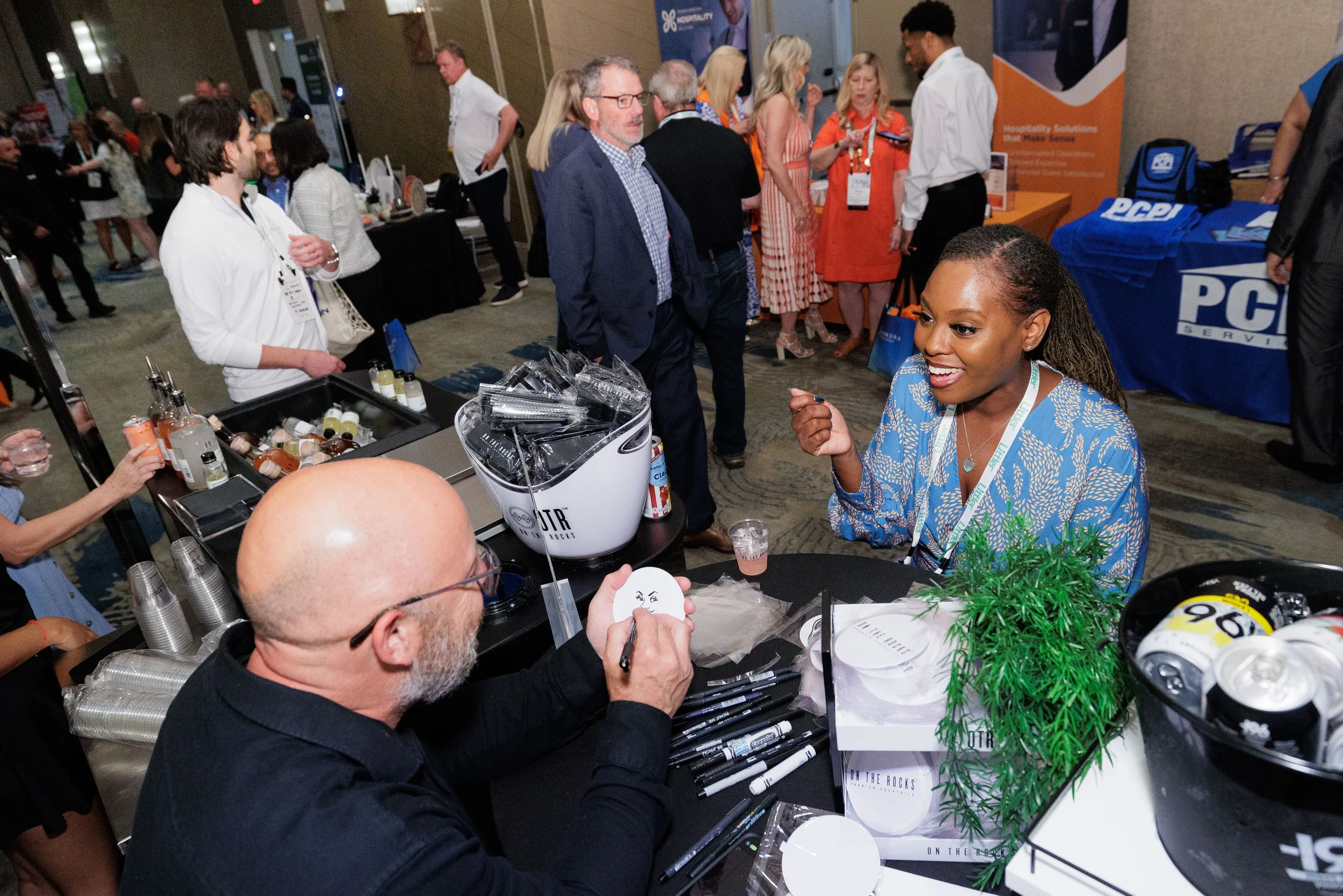 Attendee with lanyard watches custom art being drawn at exhibitor booth during Chicago corporate trade show