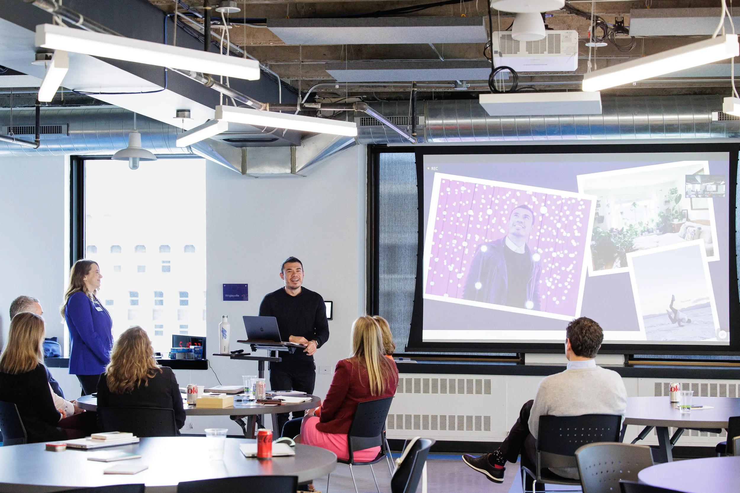Speaker presents beside a large projection screen to a small seated group at Chicago corporate event