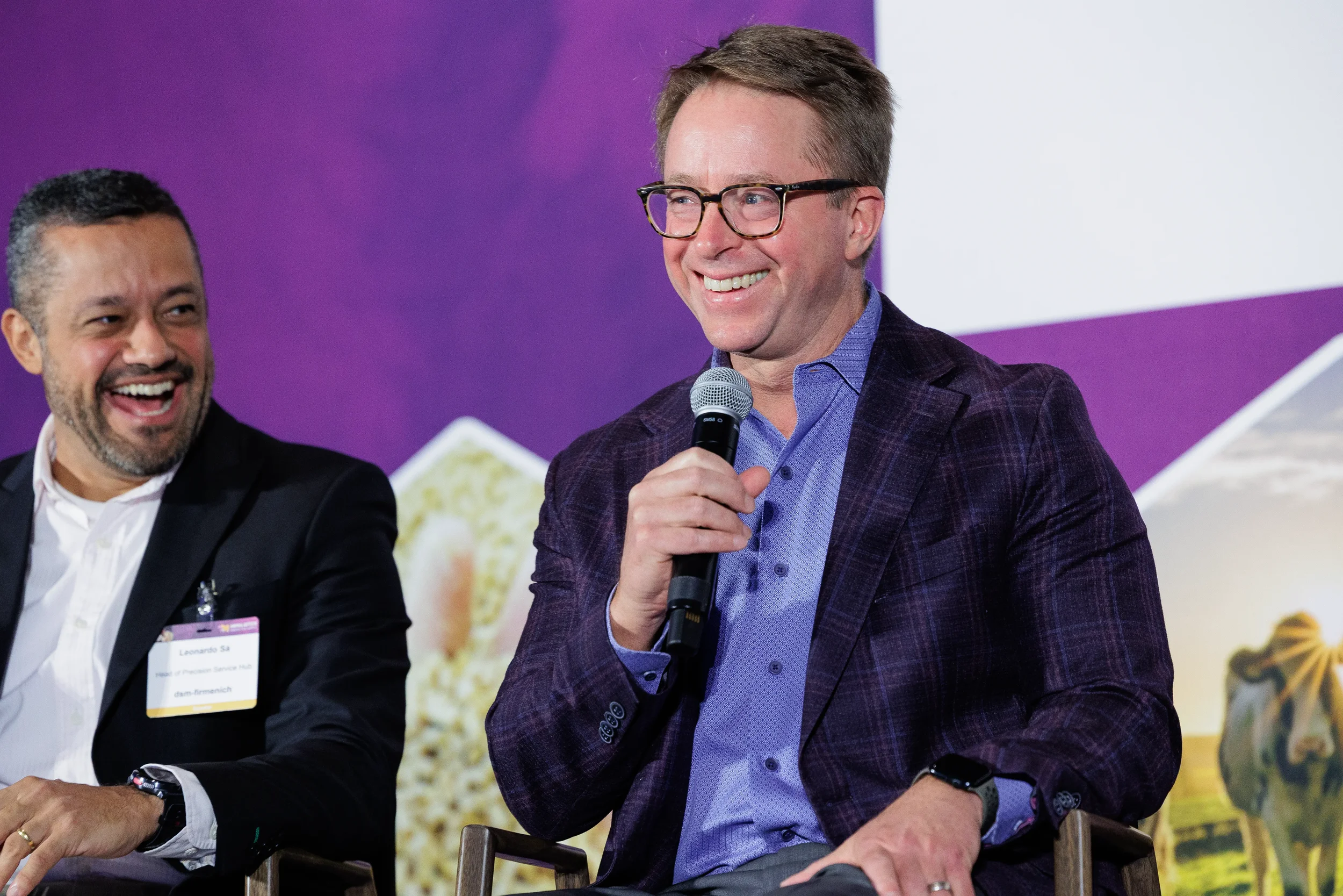Panelist speaks into microphone while seated beside colleague at Chicago corporate conference