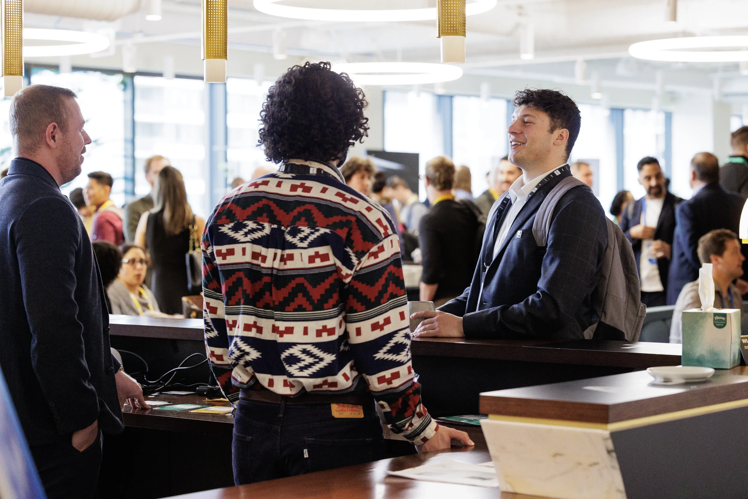 Attendees chat at counter in busy lounge during networking reception at Chicago corporate conference