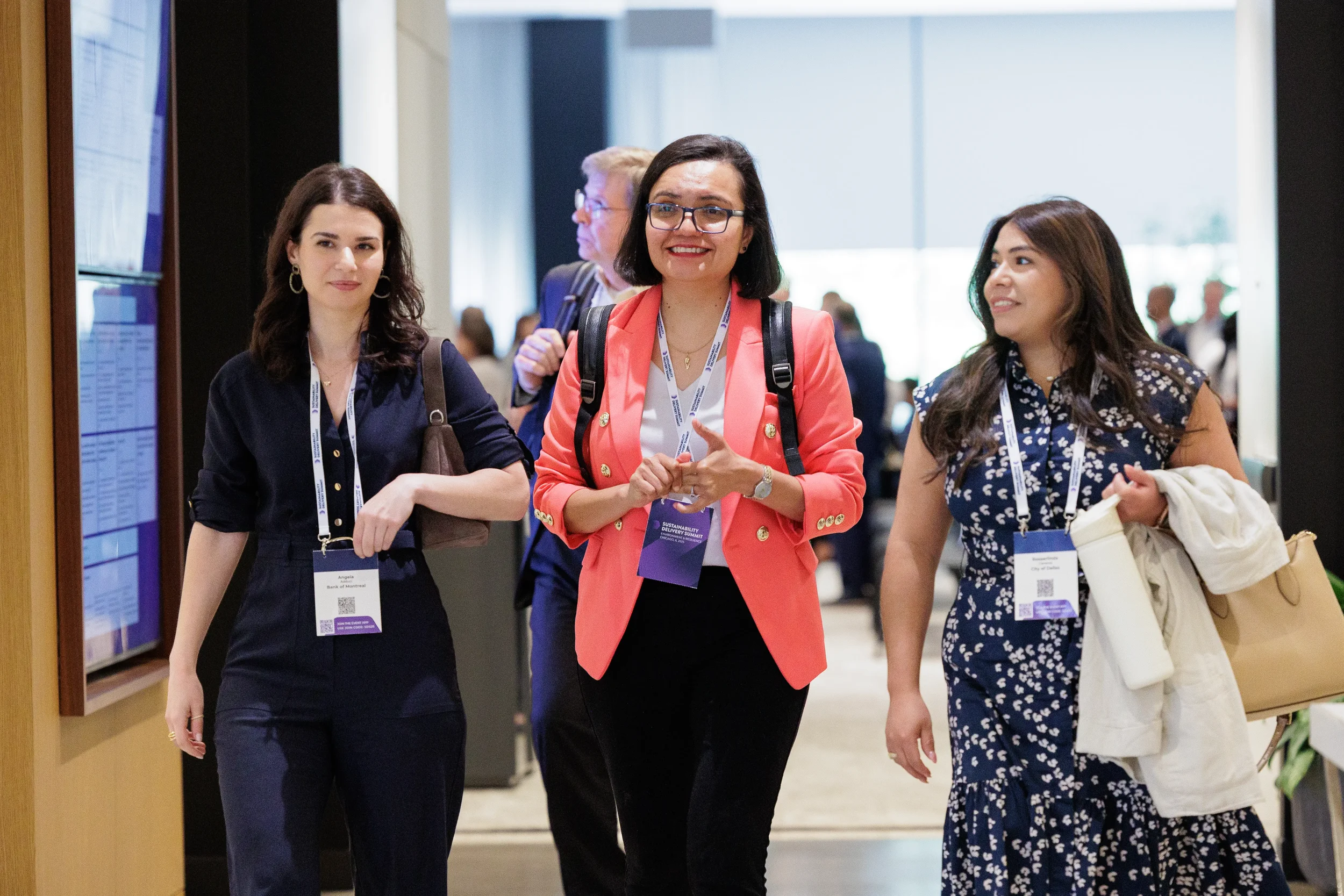 Three attendees walk and smile together in hallway during Orlando corporate conference event