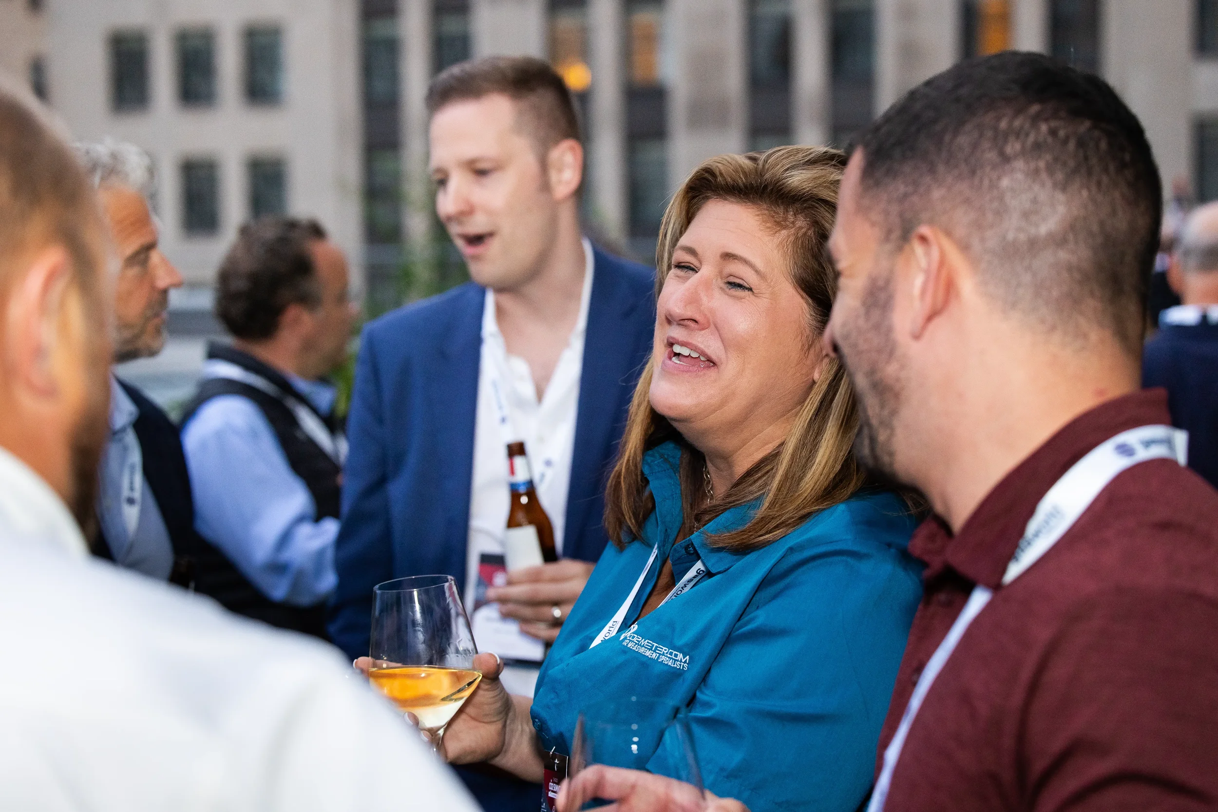 Attendees laugh and converse with drinks in hand at outdoor networking reception during Chicago industry conference