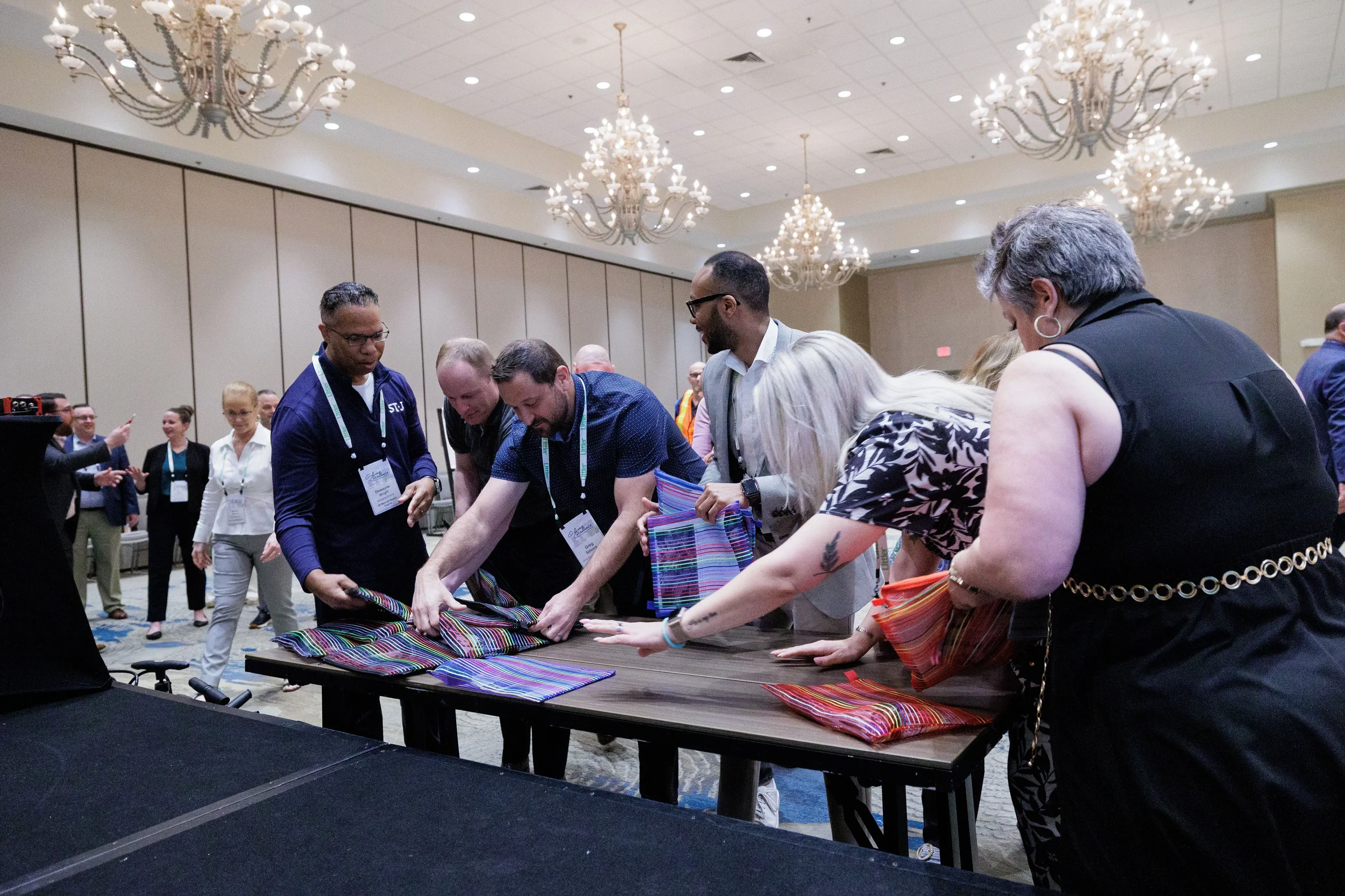 Attendees with lanyards collaborate around activity table in chandelier ballroom at Chicago corporate conference