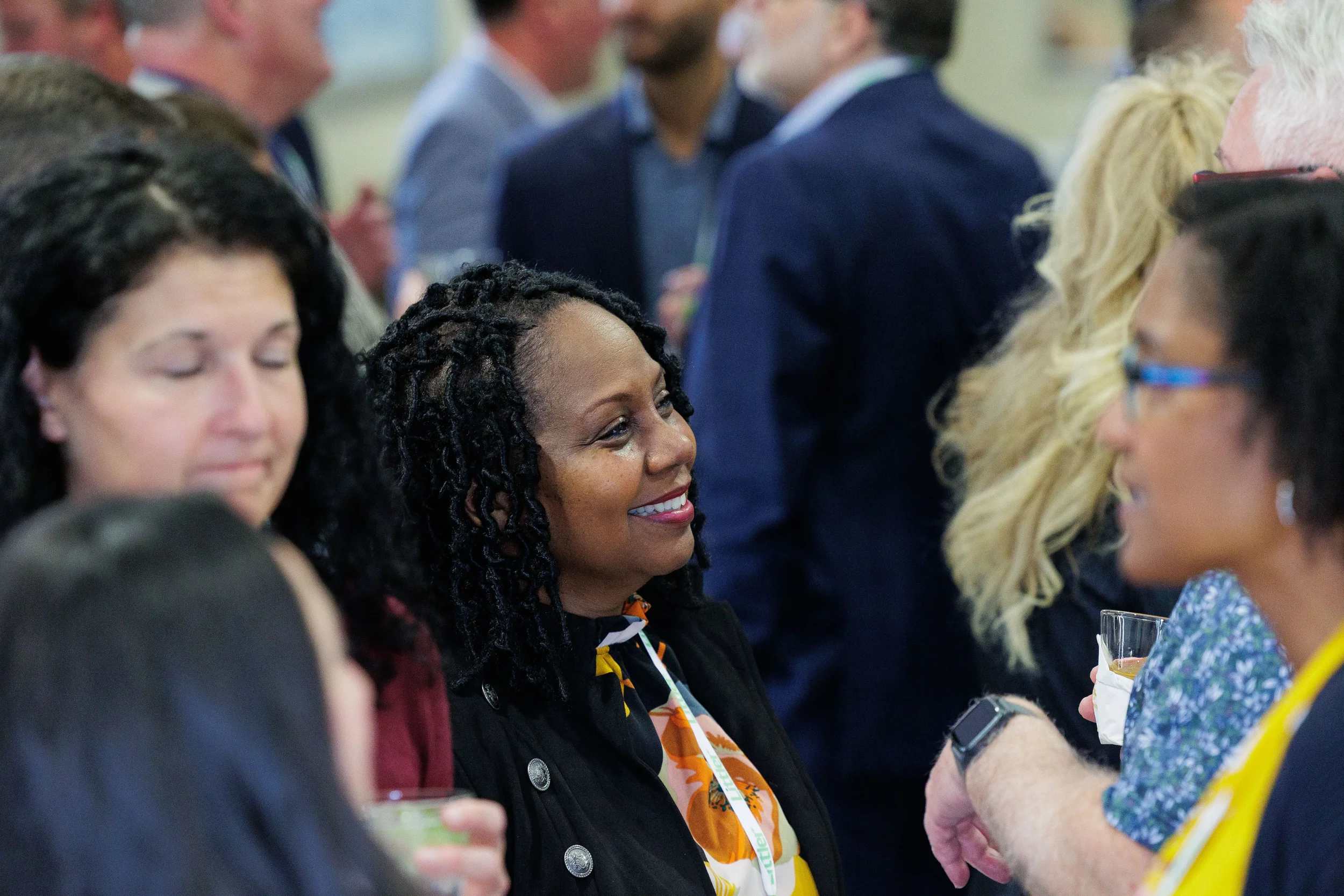 Attendee with lanyard smiles warmly while mingling in crowd at Chicago corporate conference reception