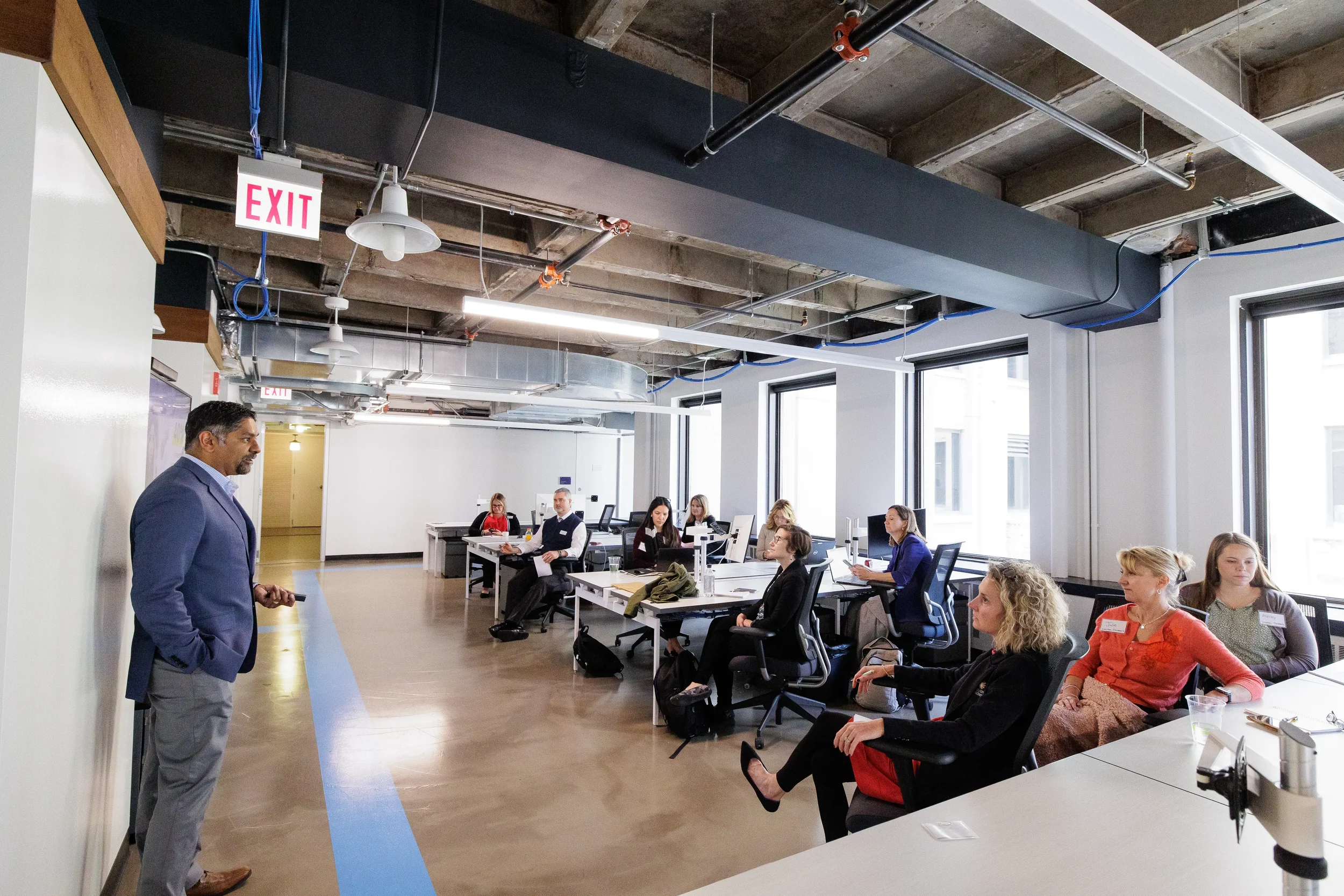 Speaker presents to small seated group in bright modern workspace during Chicago corporate event session
