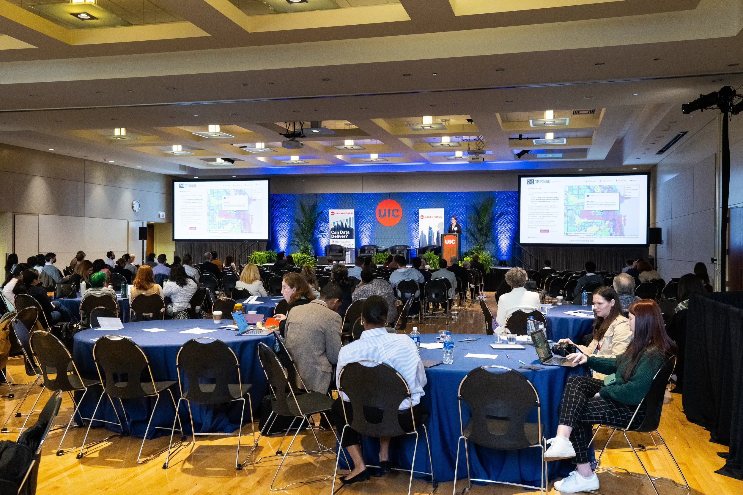 Wide view of audience seated at roundtables watching presentation at Orlando corporate event
