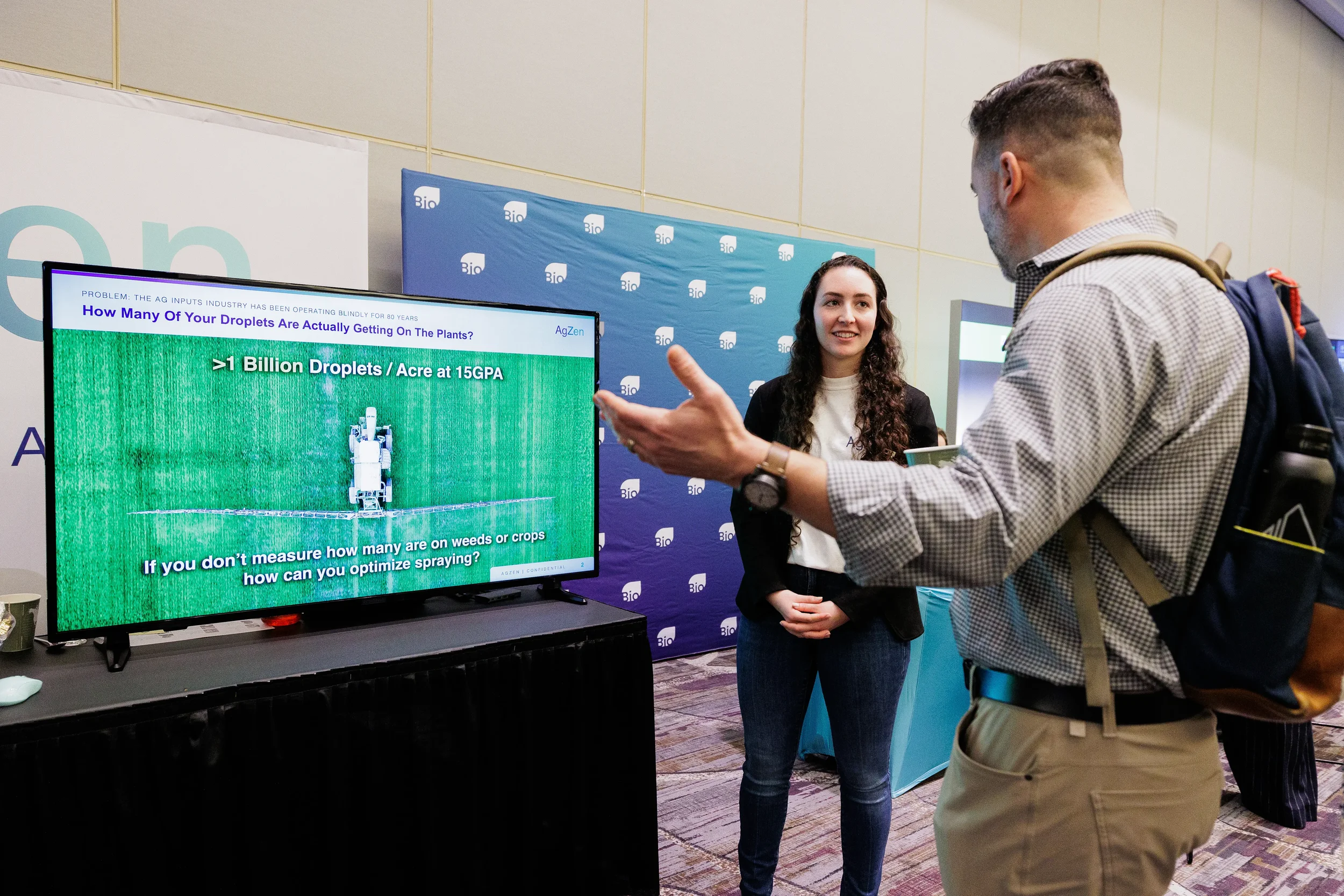 Exhibitor presents screen demo to attendee at trade show booth at Chicago corporate industry conference