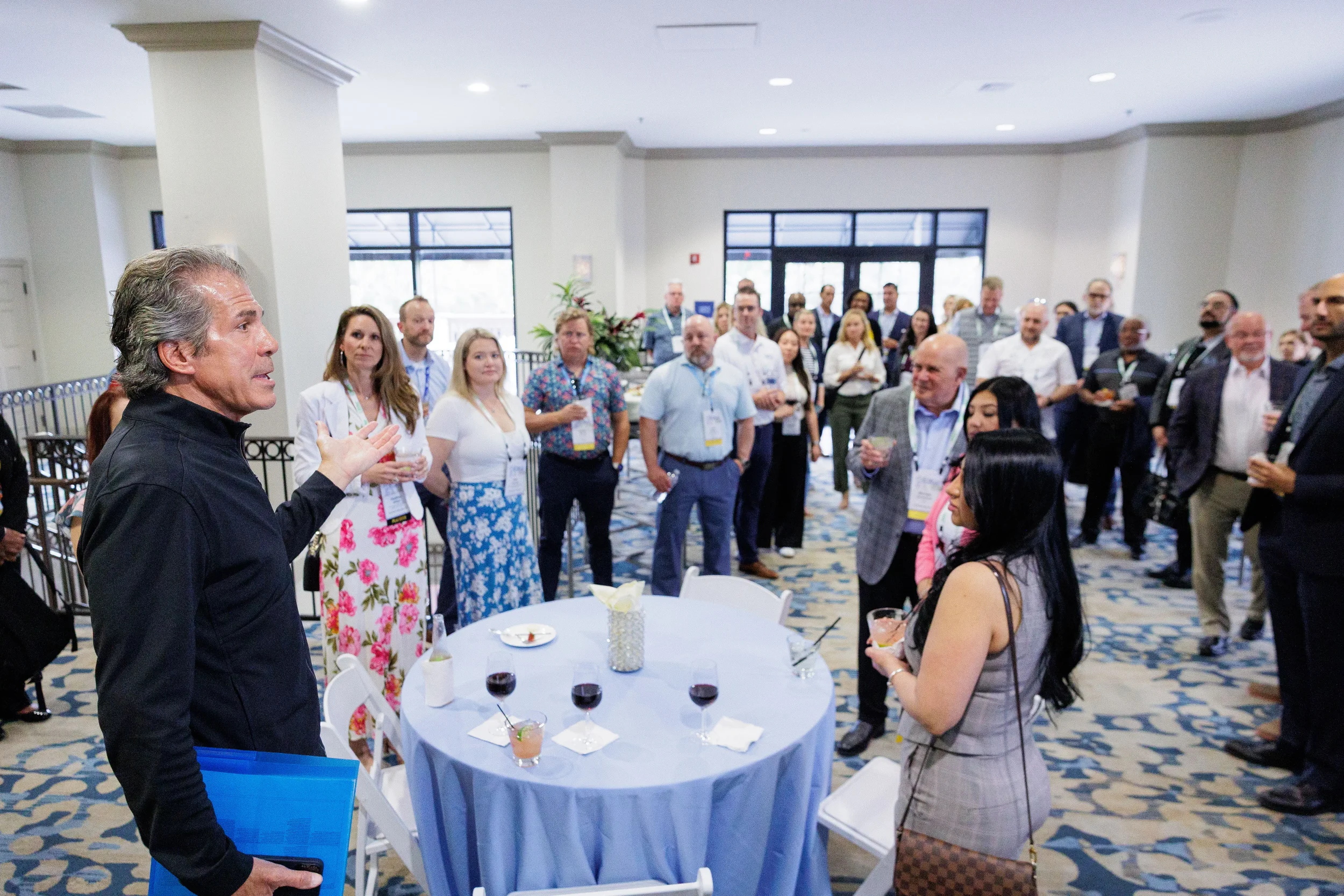 Speaker gestures while addressing large crowd of attendees at Chicago corporate conference cocktail reception