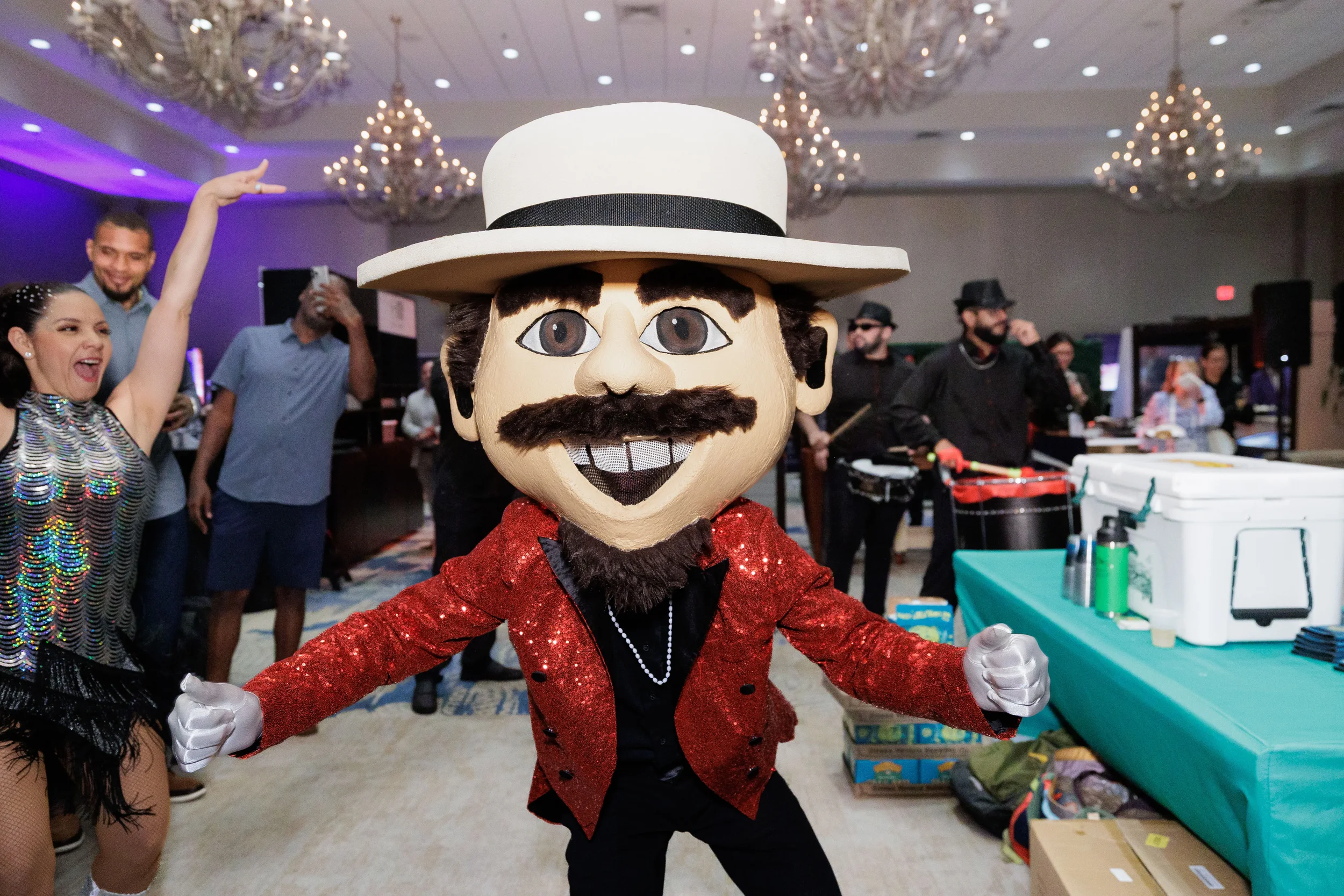 Oversized mascot character in red sequin jacket dances at Chicago corporate conference reception