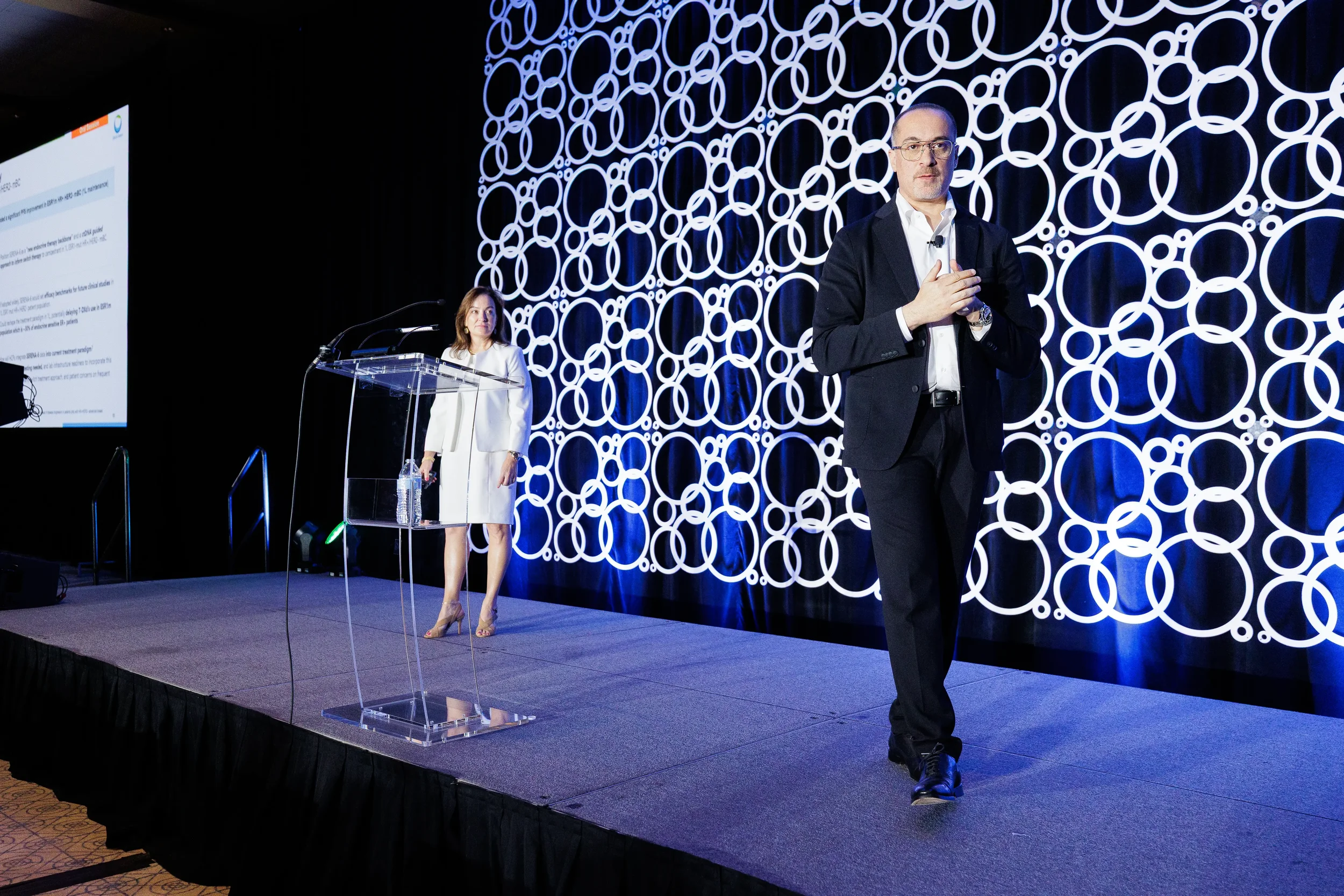 Two speakers present on stage with illuminated circular backdrop at Chicago industry conference