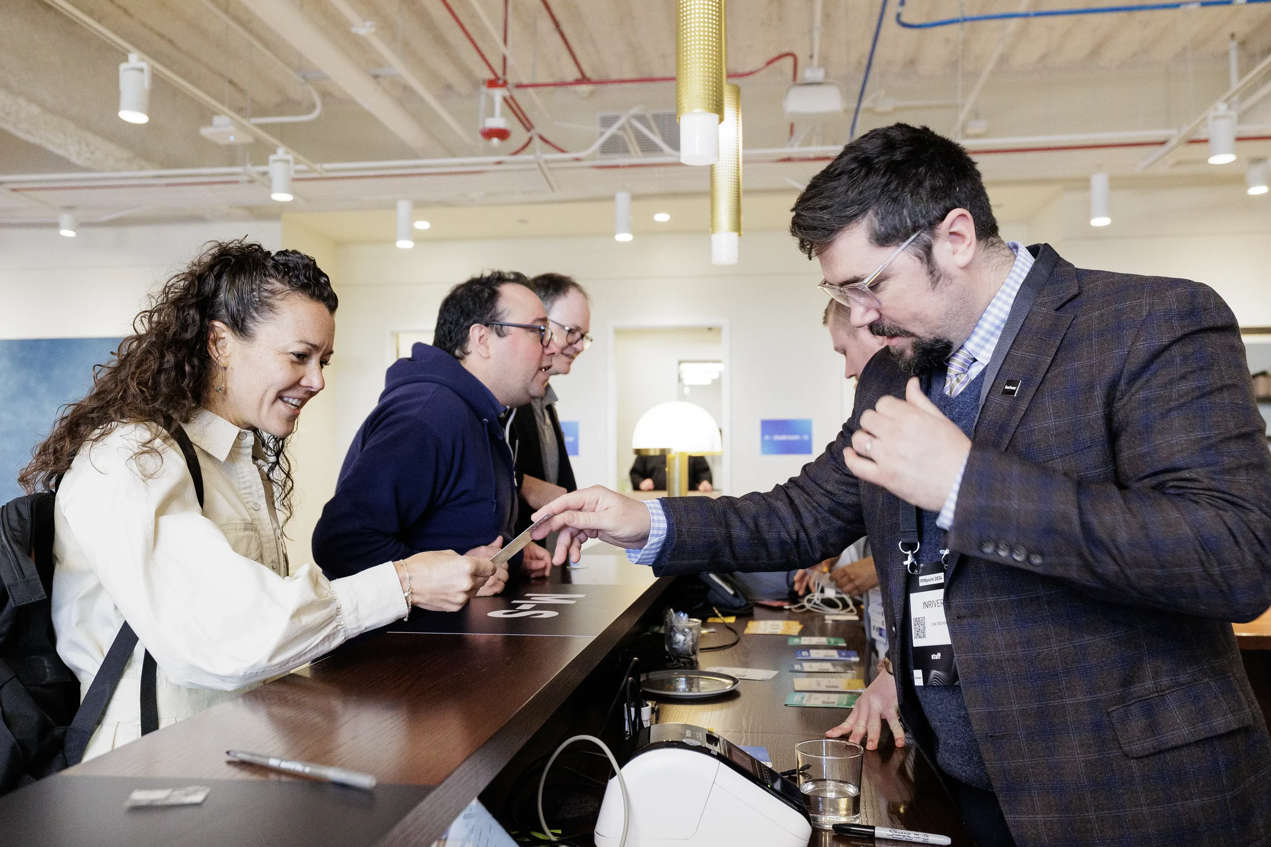 Attendee hands card to registration staff at check-in desk during Chicago industry conference