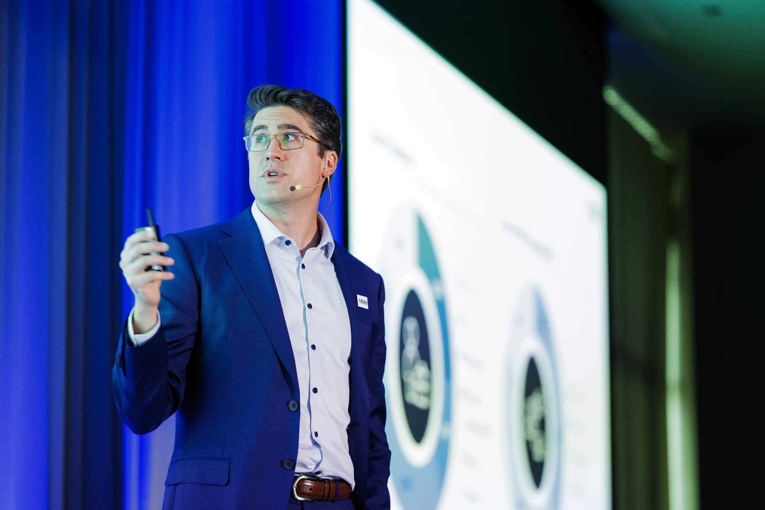 Speaker looks up at screen while holding clicker during presentation at Orlando corporate conference
