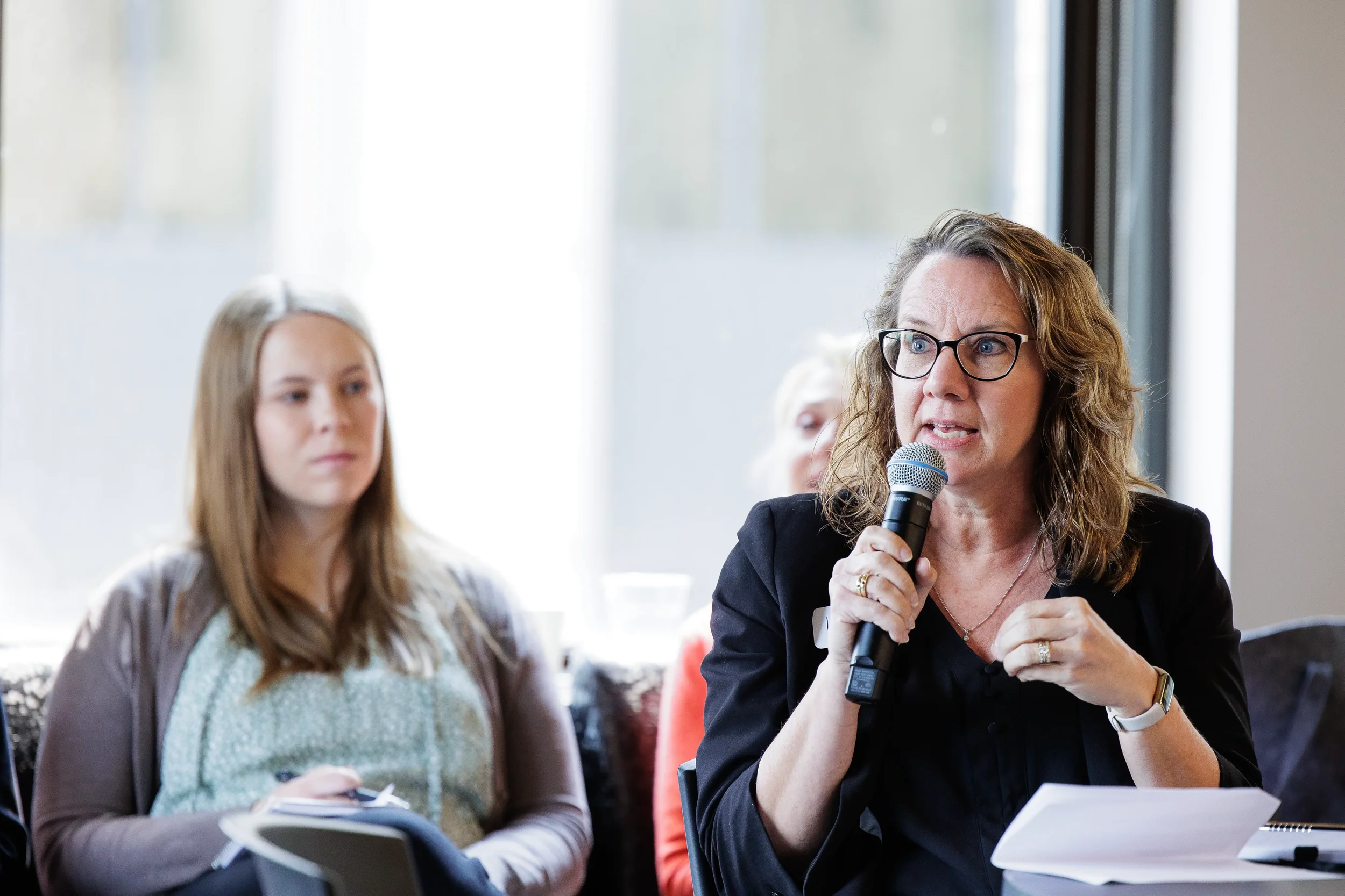 Female attendee speaks into microphone while seated beside another attendee at Orlando corporate event