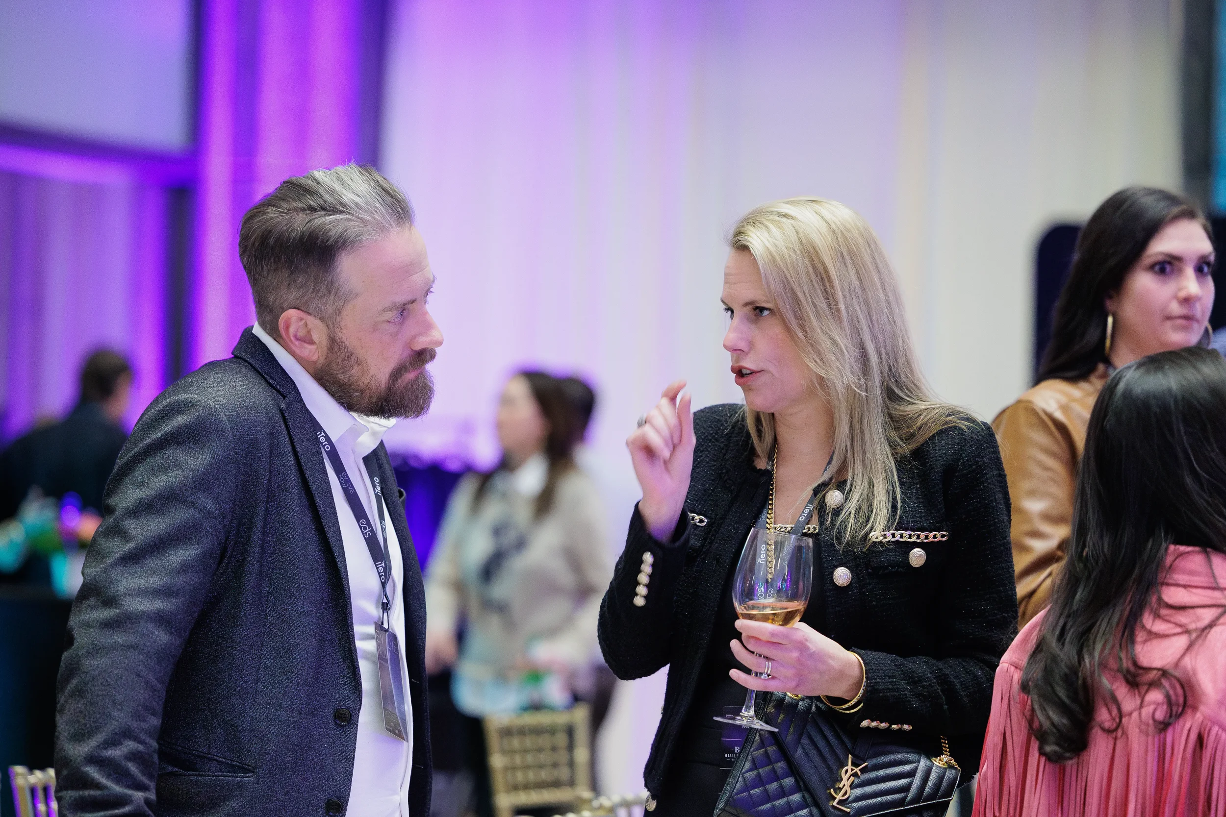 Male and female attendees with lanyards converse during networking reception at Orlando corporate event