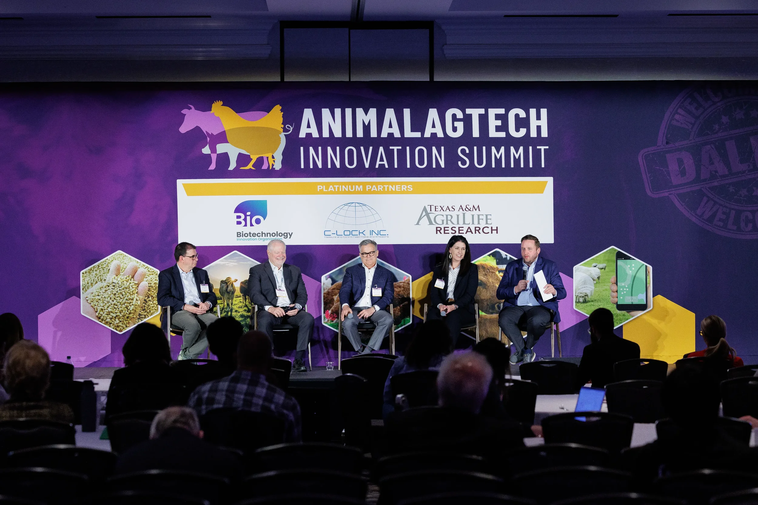 Five panelists seated on stage before full event banner at Orlando industry summit
