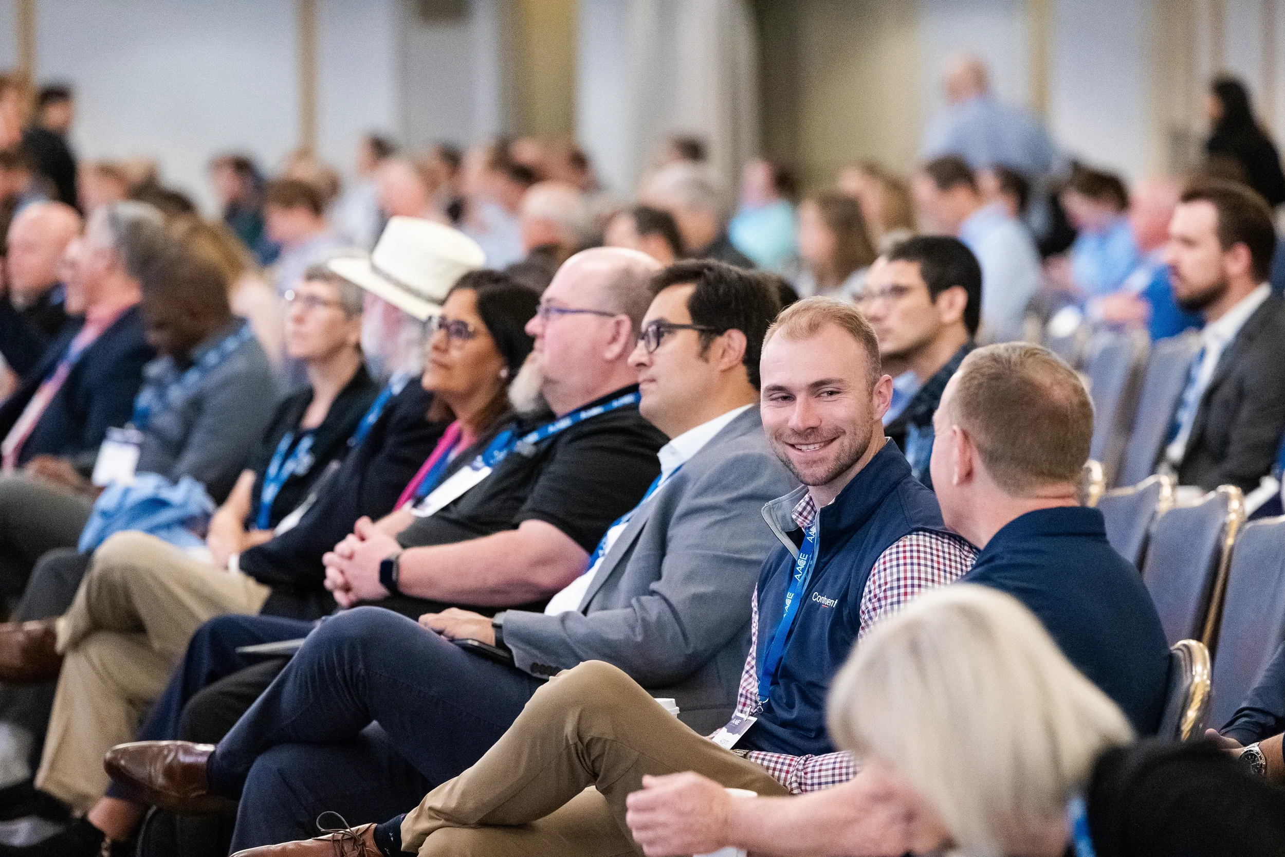 Attendees seated during general session at Orlando conference with smiling professional in foreground