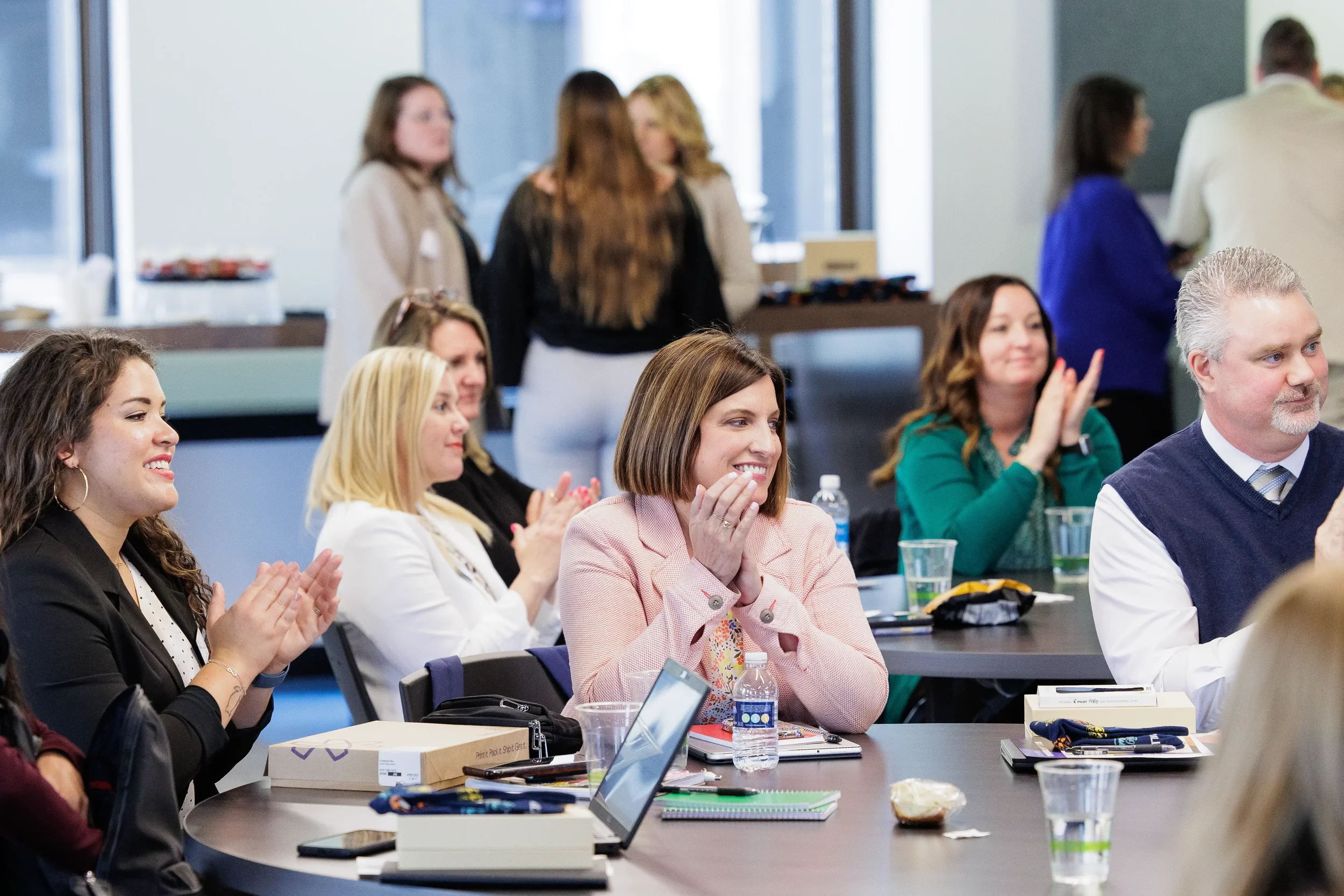 Attendees applaud and smile at tables during an engaging session at Orlando corporate event venue