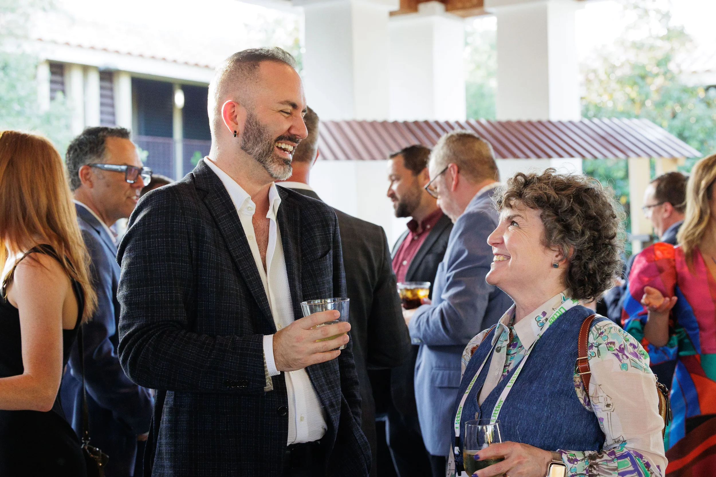 Two attendees laugh together over drinks at outdoor pavilion networking reception at Chicago conference
