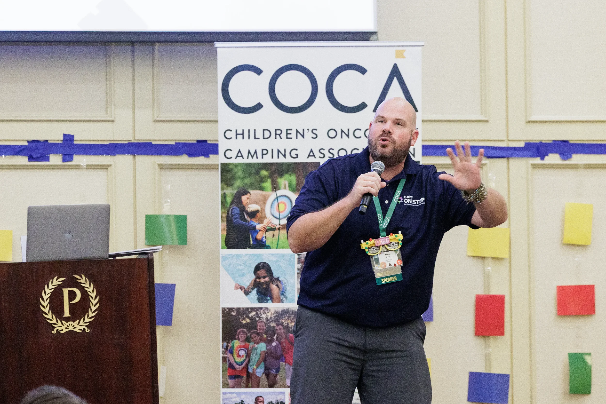 Speaker gestures while addressing audience with microphone at Chicago nonprofit conference event