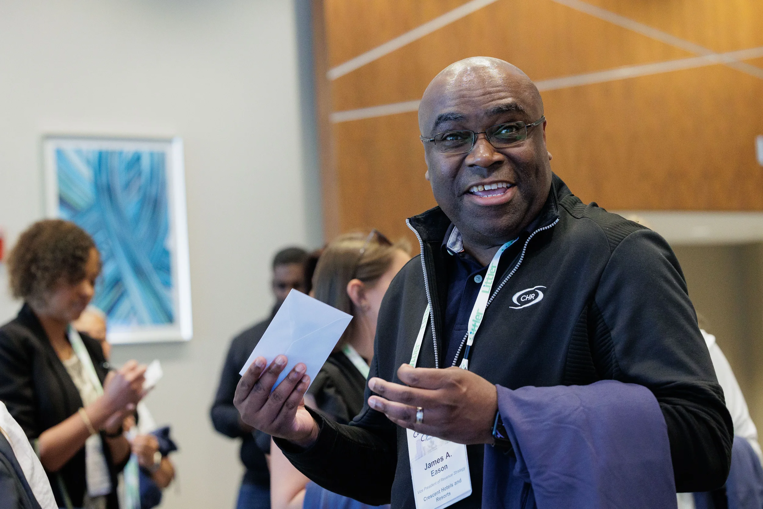 Smiling attendee with lanyard holds card while chatting at Chicago corporate conference foyer