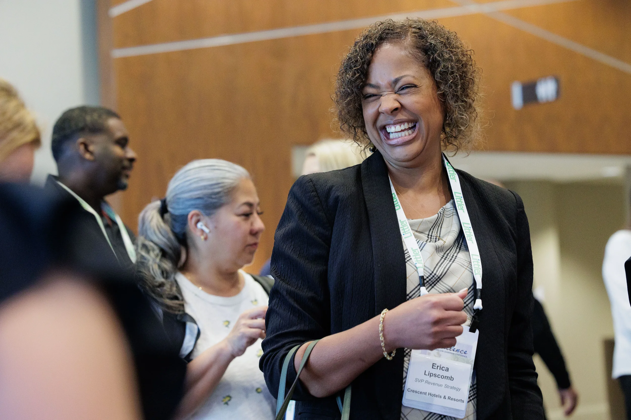Attendee with lanyard laughs broadly while networking in crowd at Orlando corporate conference