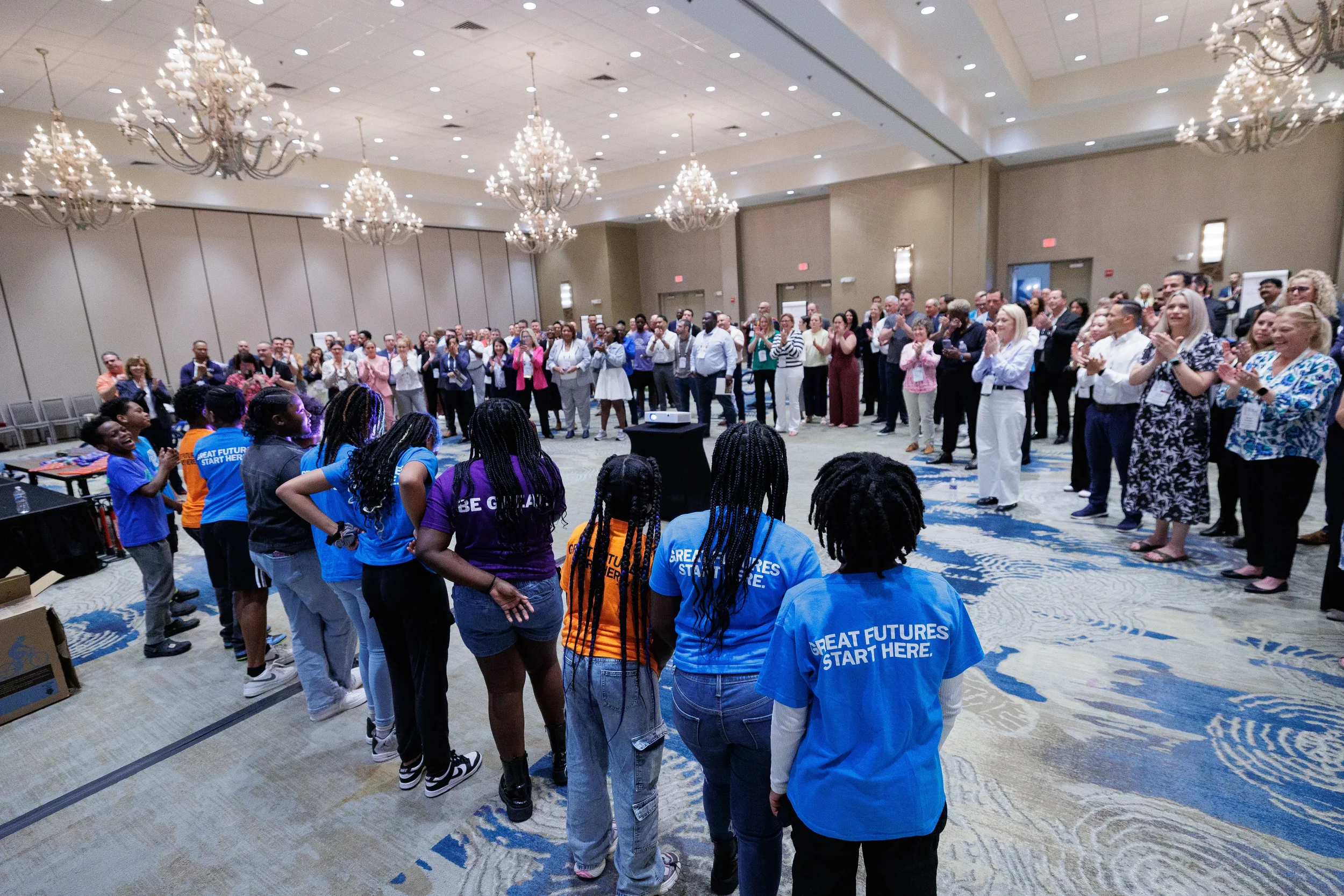 Youth group in matching shirts receives standing ovation from conference attendees at Orlando corporate event