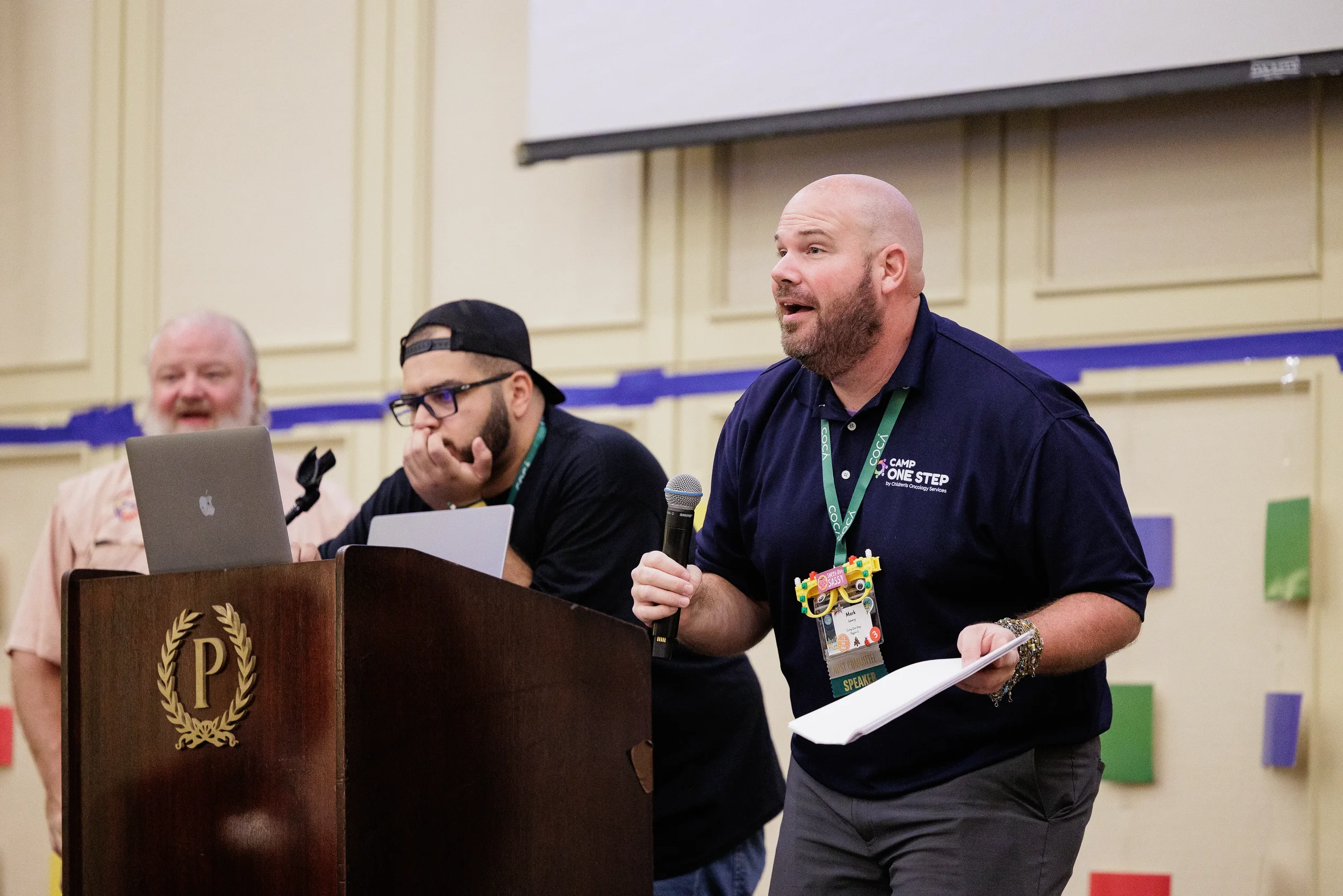 Speaker holds microphone beside podium while addressing audience at Orlando nonprofit conference event