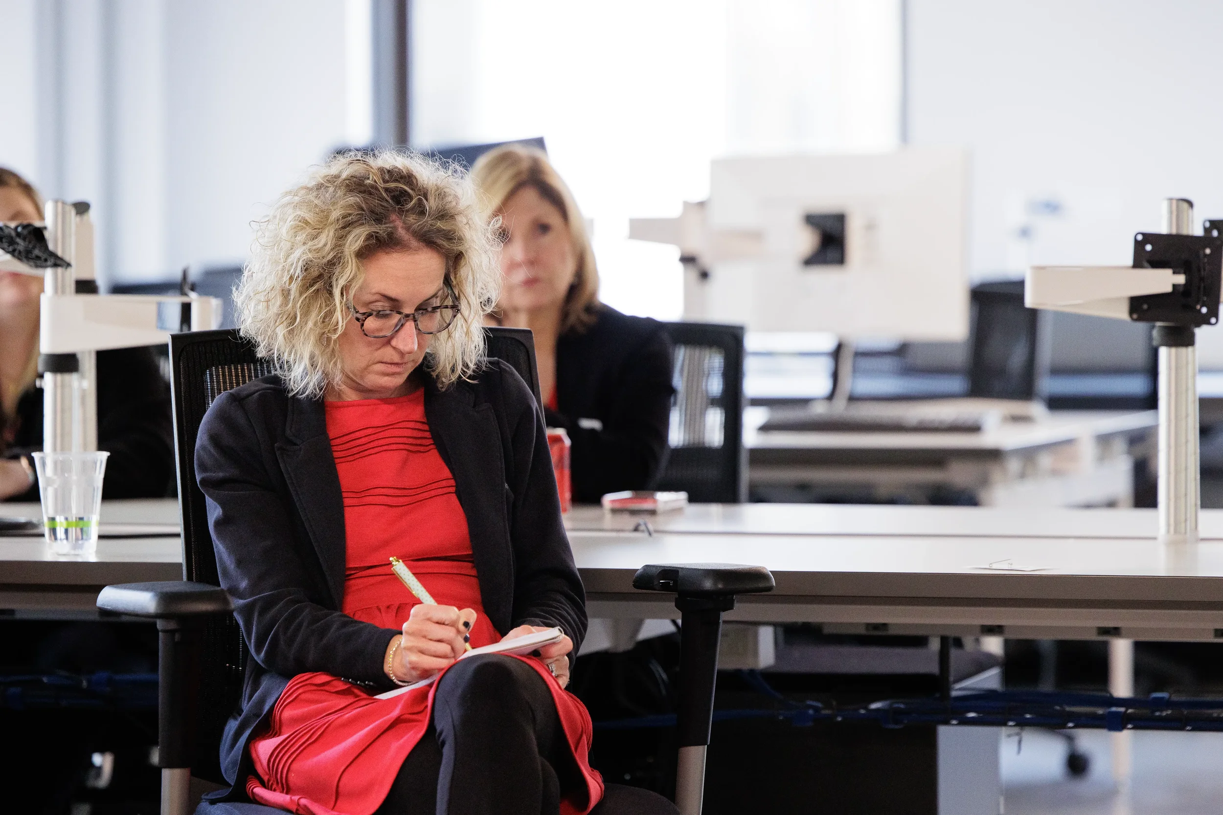 Female attendee focuses on taking notes with a pen during a session at Chicago corporate event