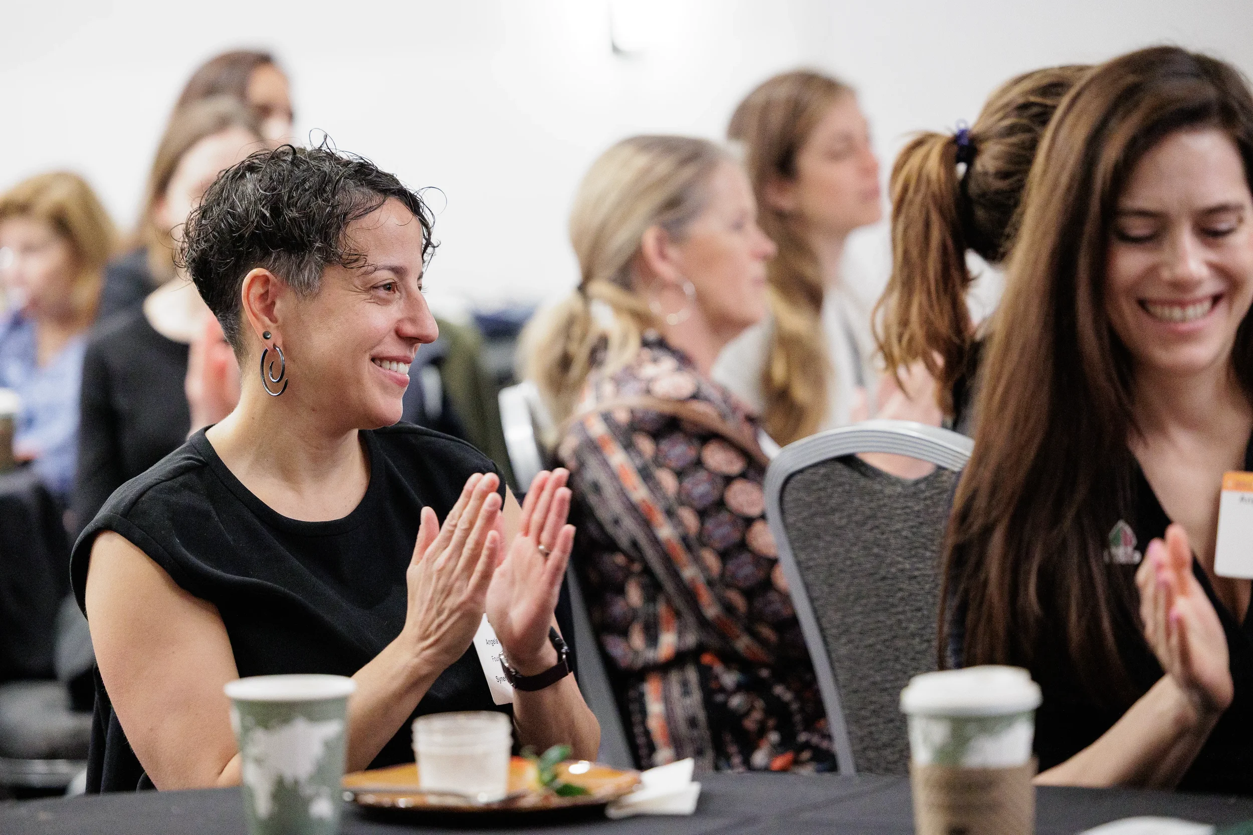 Female attendees smile and applaud during seated breakfast session at Orlando corporate conference